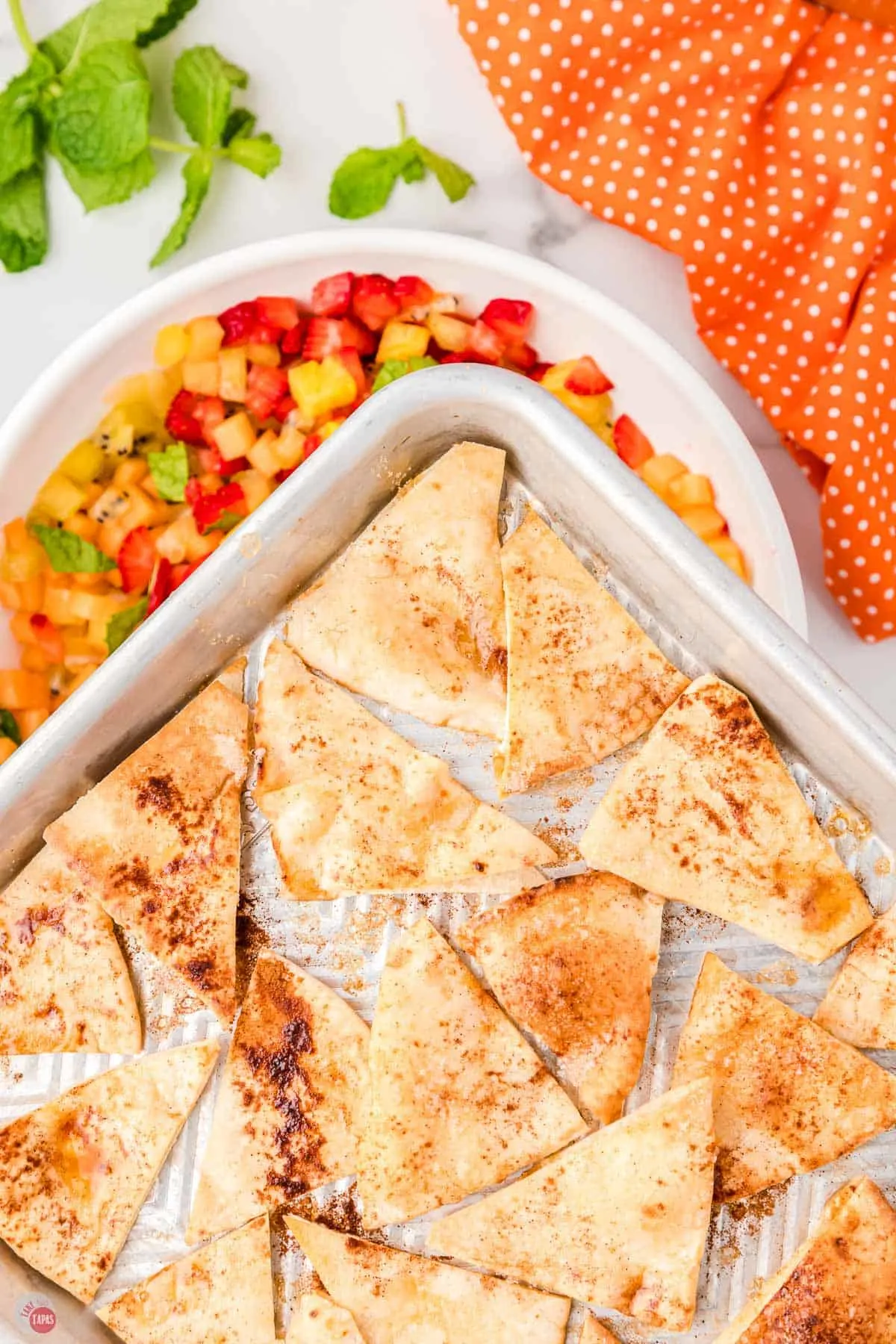 close up of pan with cinnamon chips over a bowl of fruit