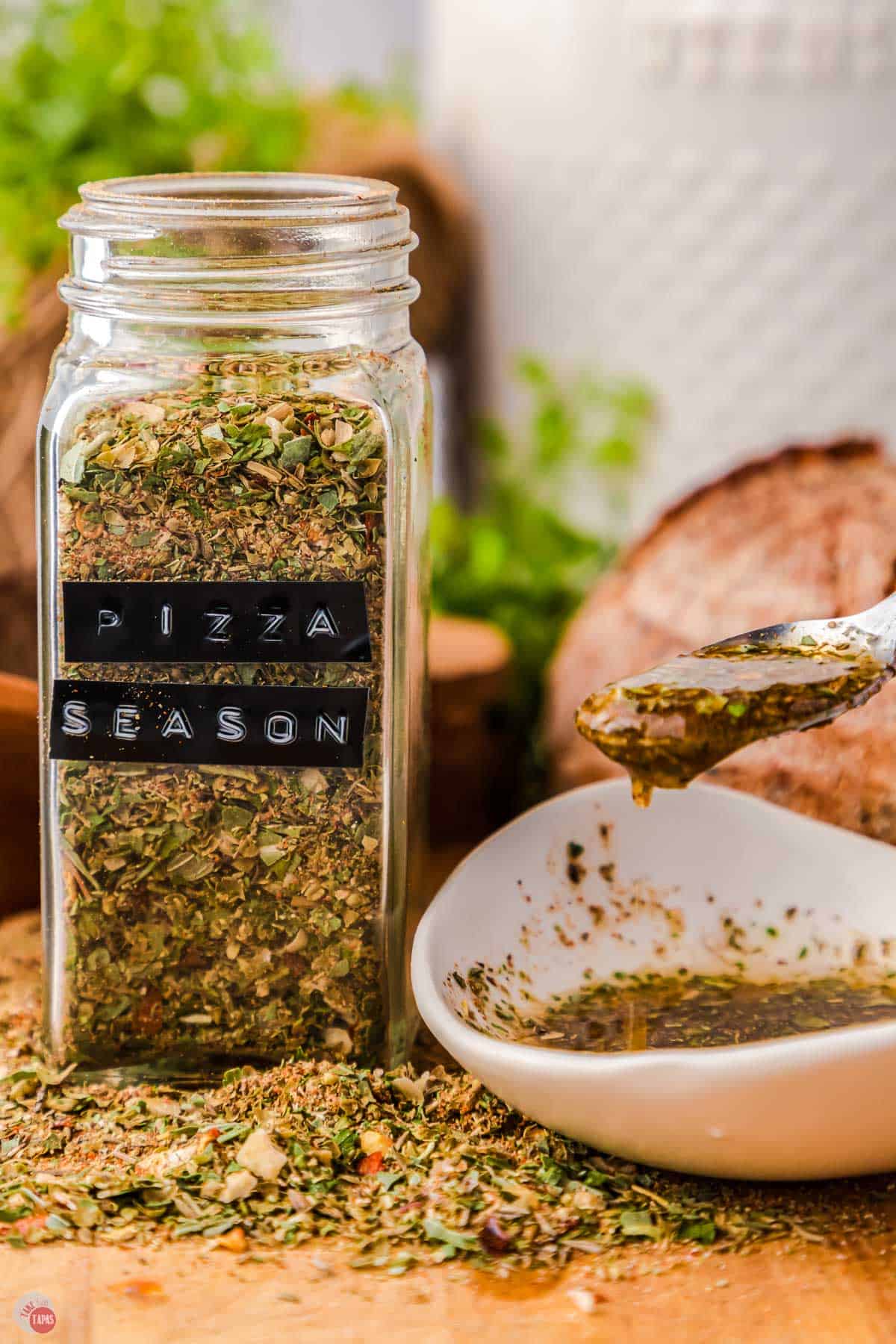 small bowl of bread dipping oil and a jar of pizza seasoning