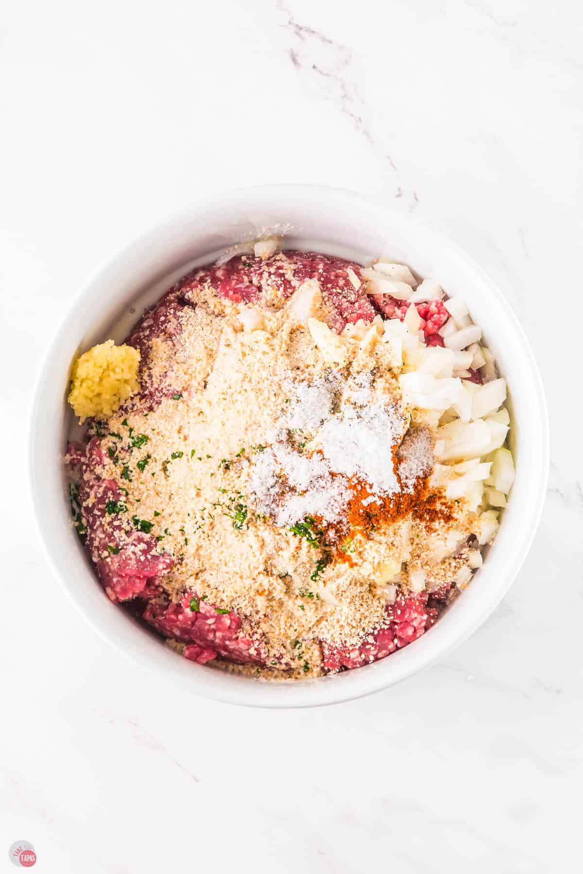 ground beef and breadcrumbs in a bowl with onion