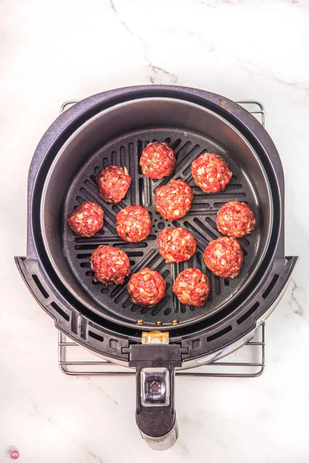 raw meatballs in an air fryer basket