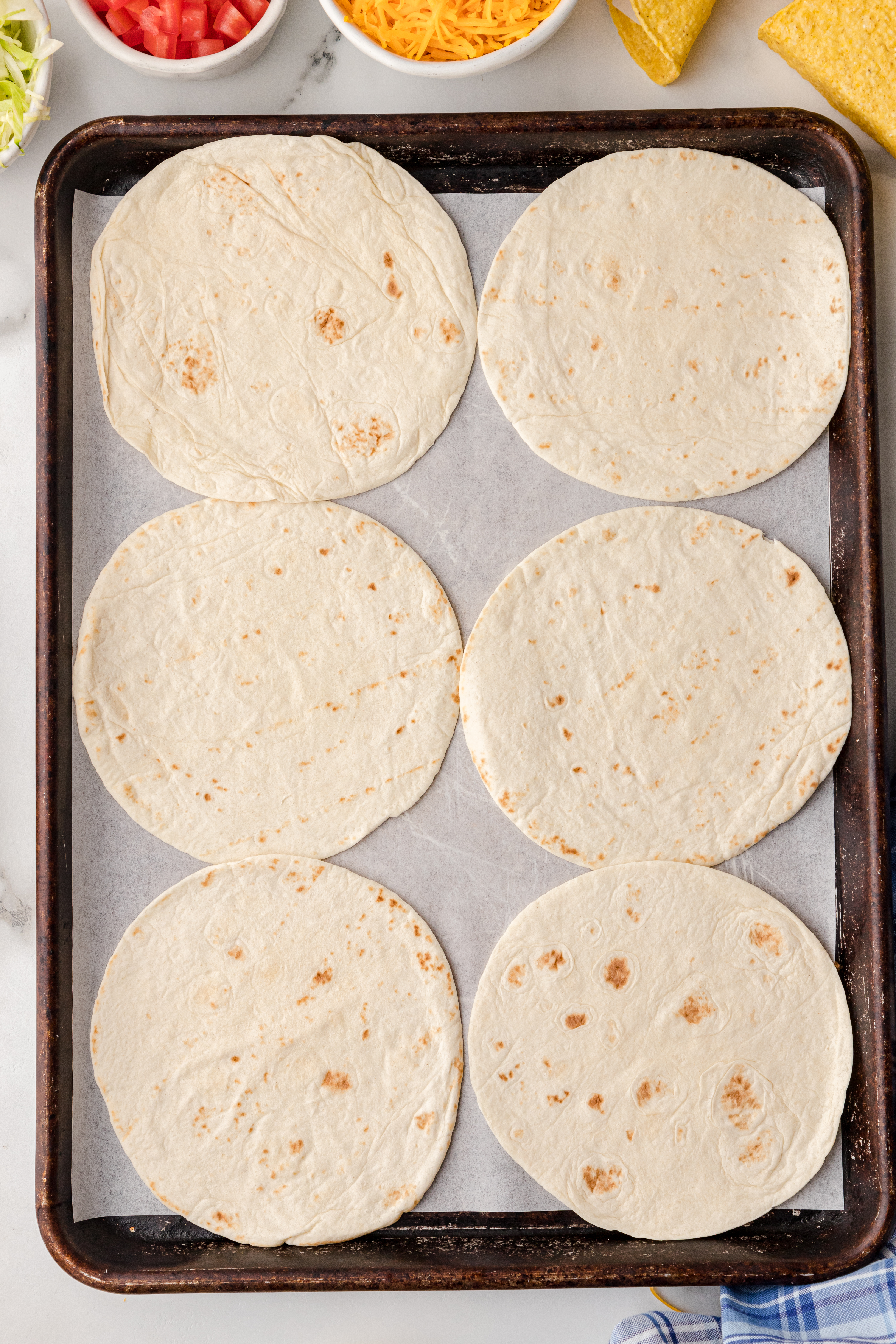 soft shell taco shells on a baking sheet with parchment paper