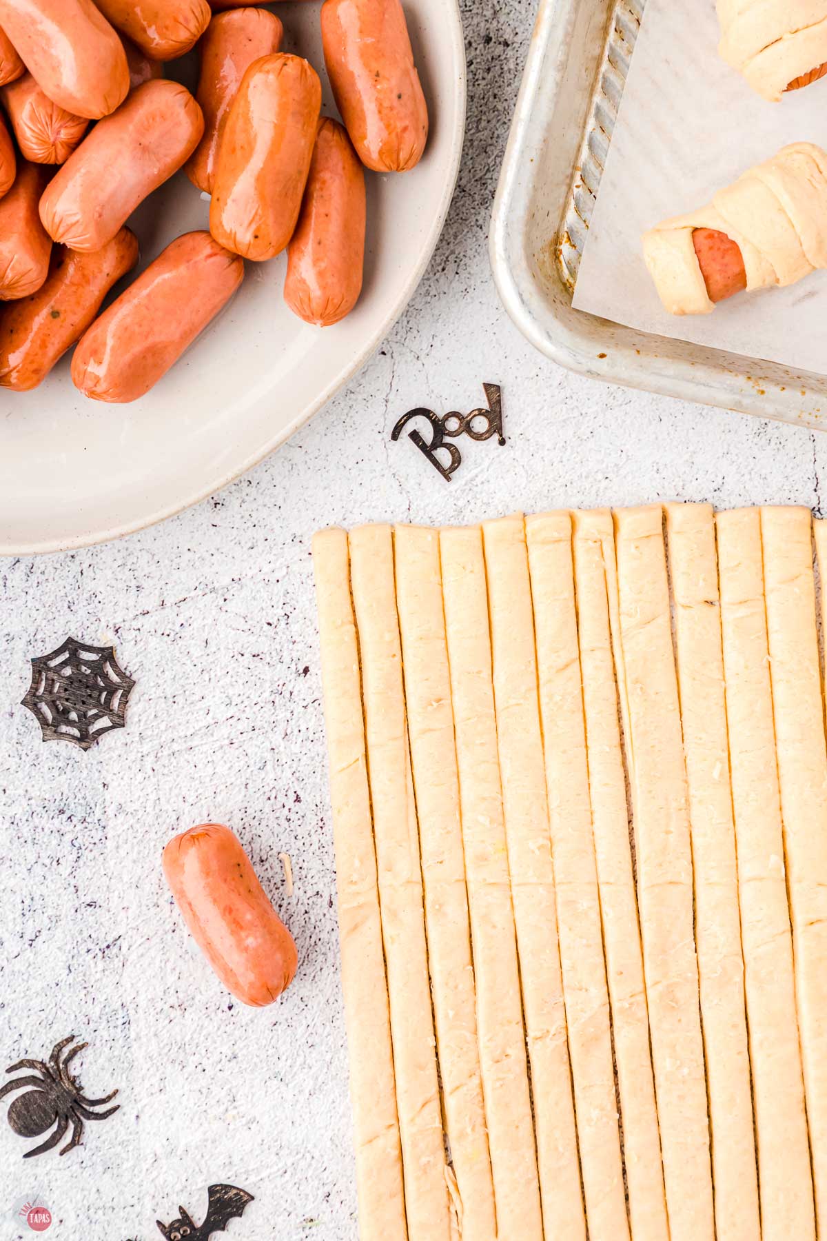 strips of crescent roll dough next to a hot dog