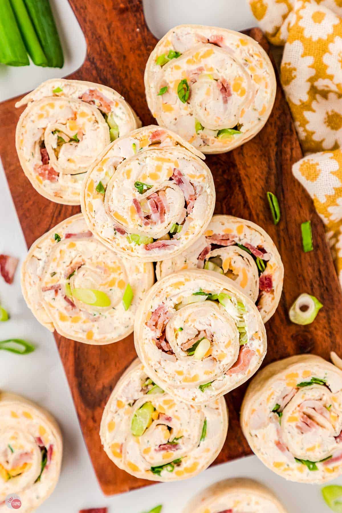 wood plank with a stack of pinwheel sandwiches