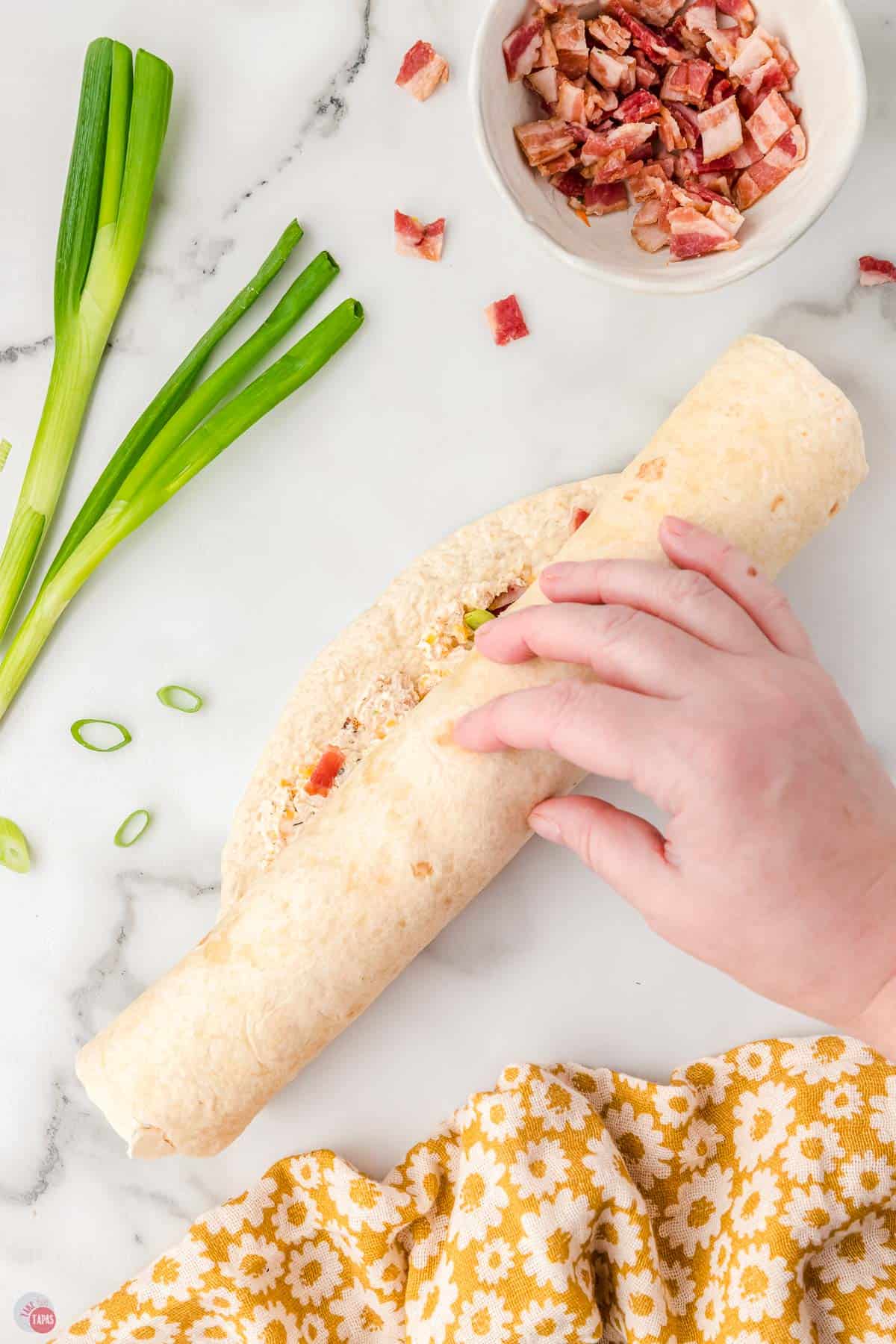 hand rolling a tortilla into a spiral