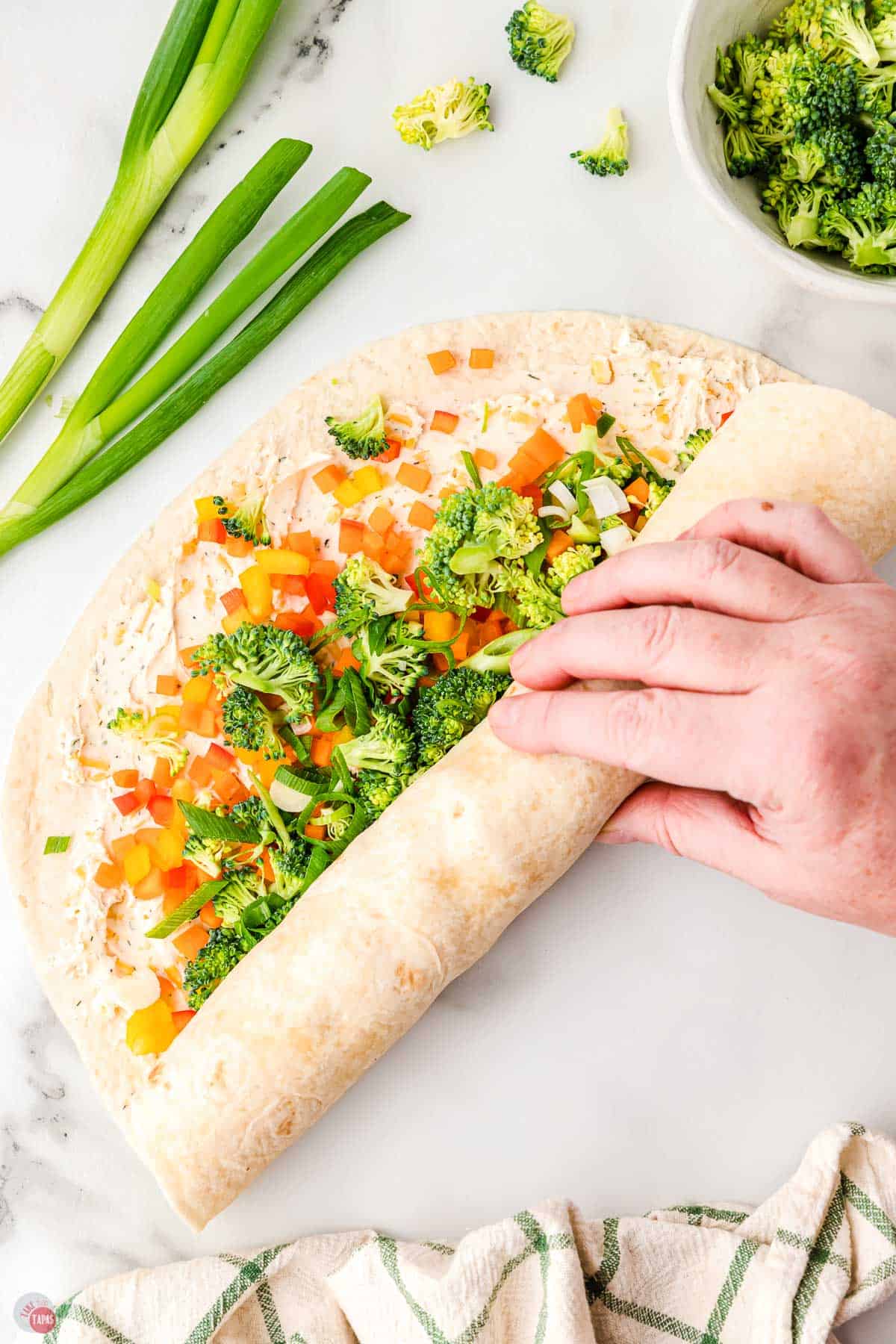 hand rolling up a tortilla pinwheel sandwich