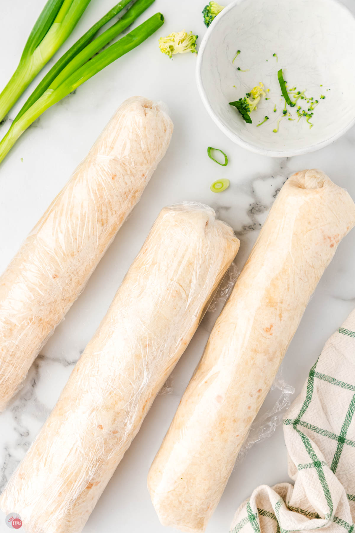 three rolled tortillas wrapped in plastic wrap