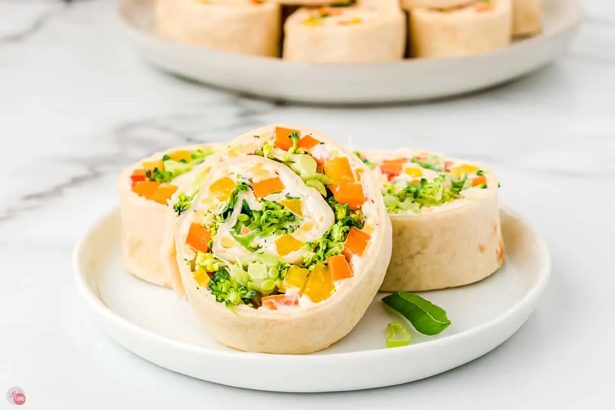 plate with three pinwheel sandwiches stuffed with fresh veggies