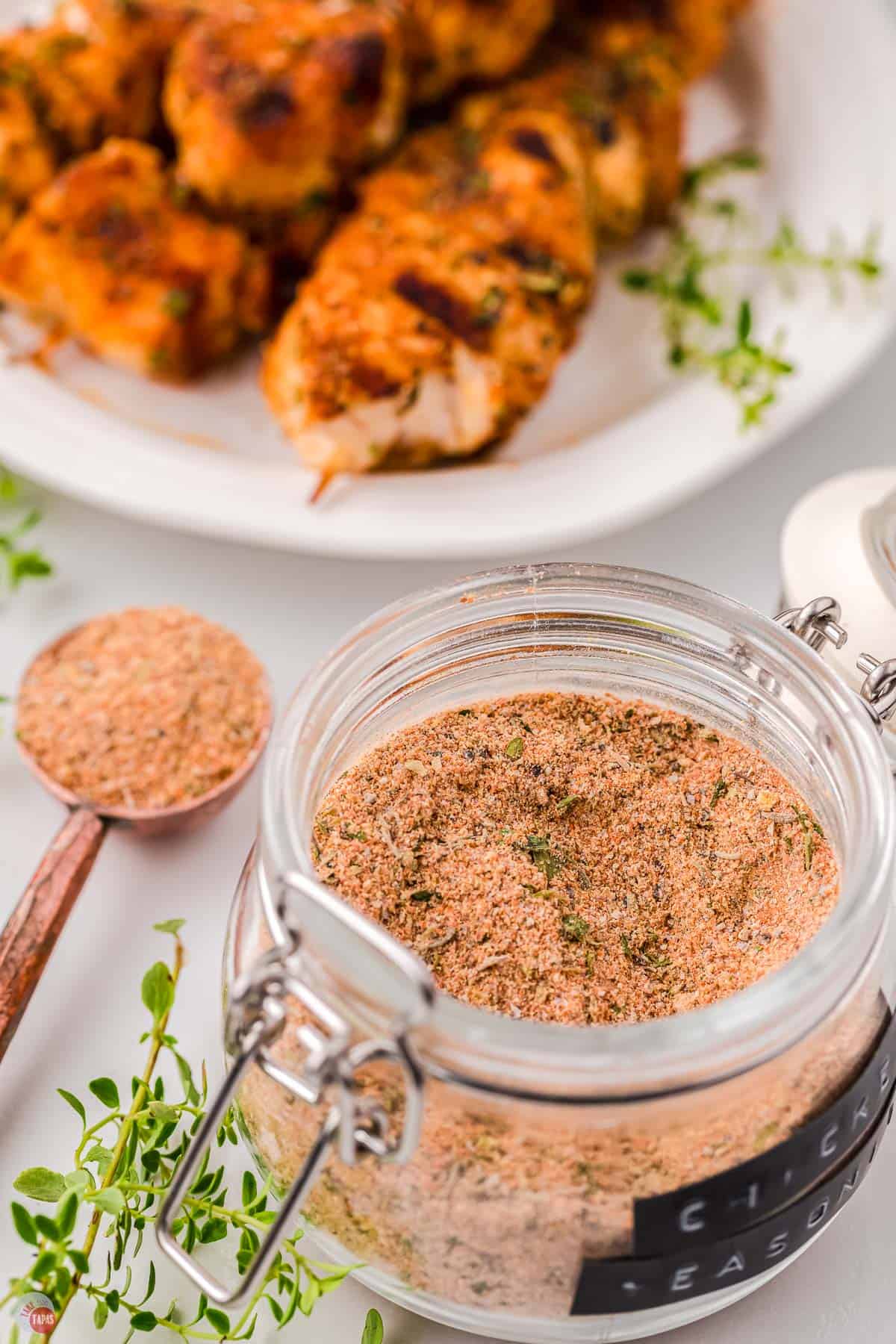 jar of seasoning with plate of chicken skewers