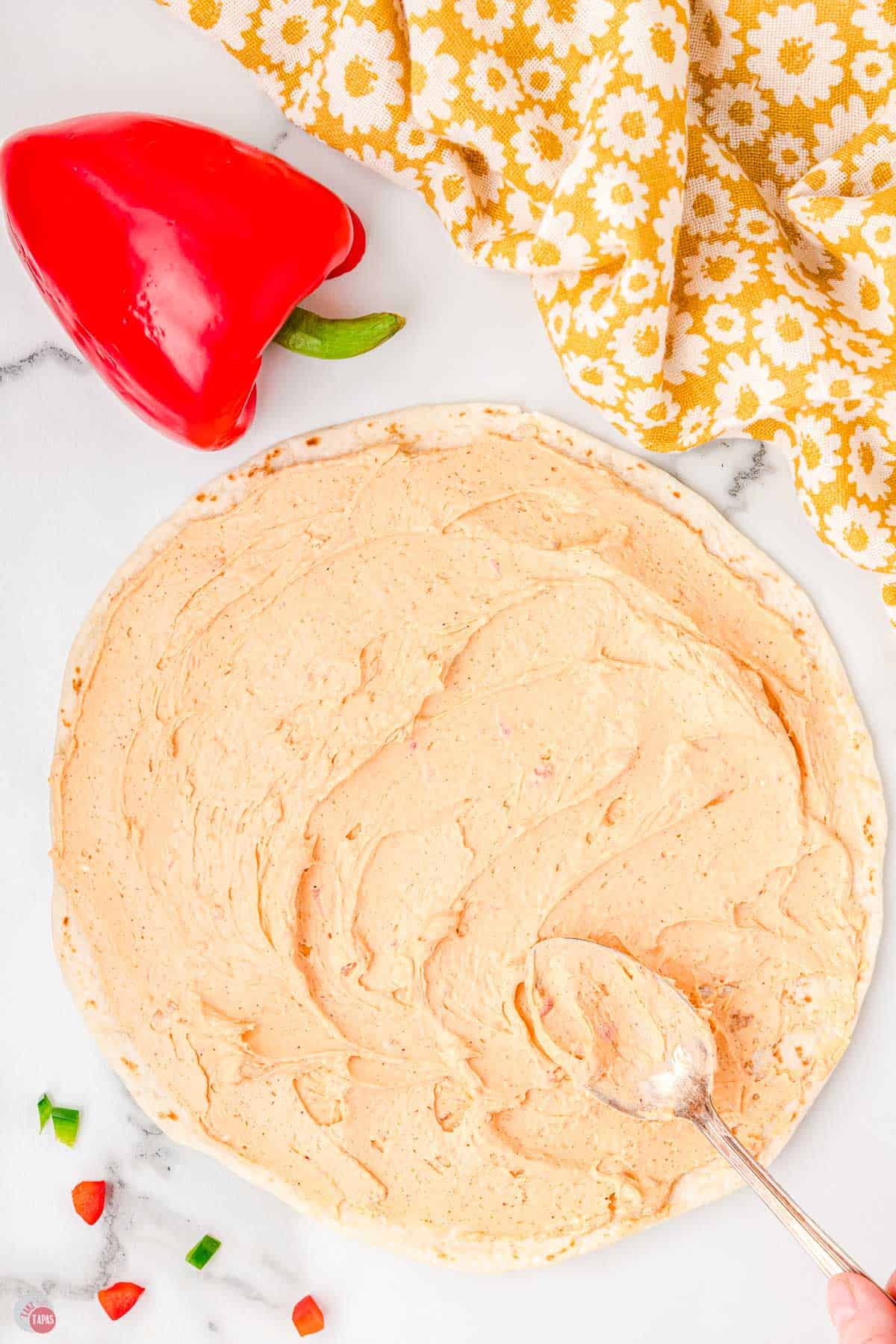 flour tortilla on a flat surface being covered in cream cheese