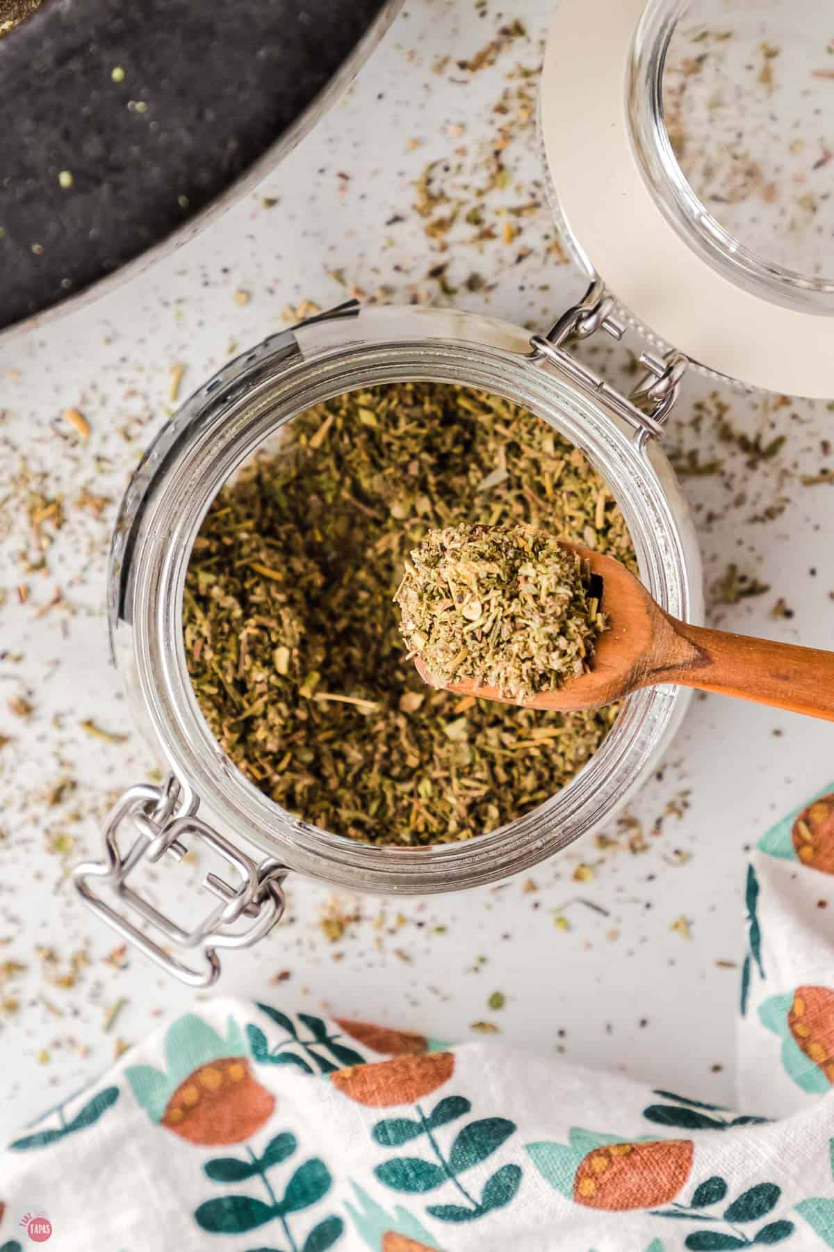 overhead of a jar of poultry seasoning with a small wood spoon