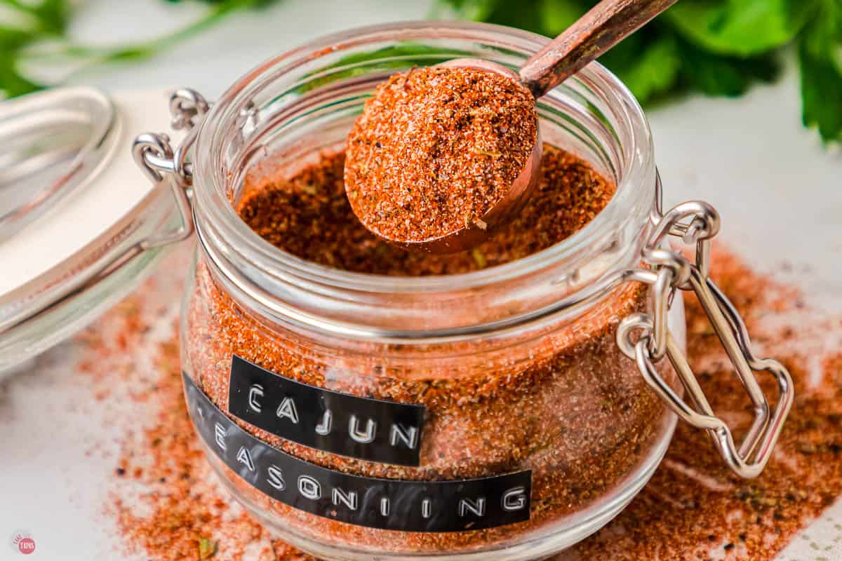 jar of cajun seasoning with a spoon taking some out