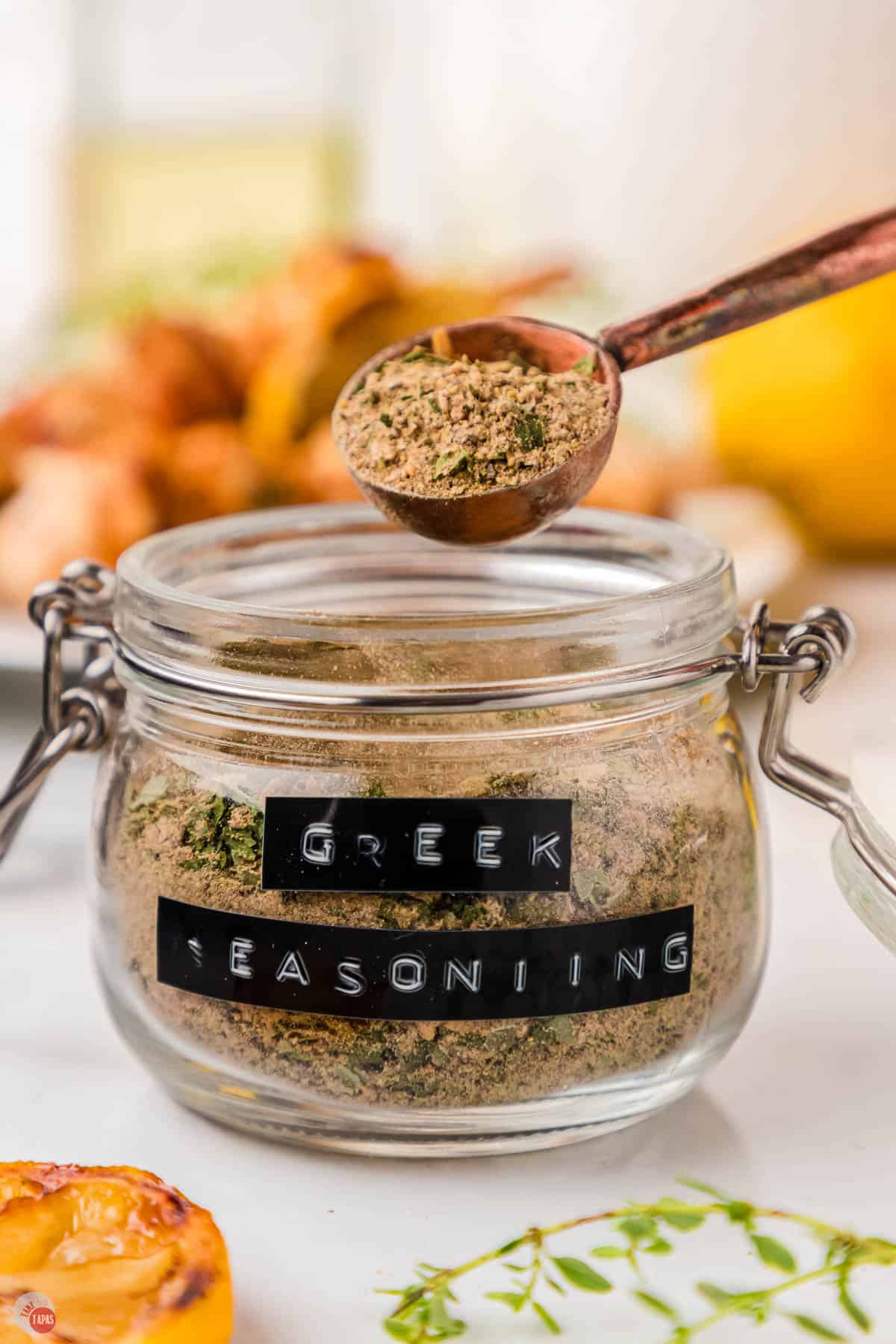 measuring spoon scooping some Greek seasoning out of a jar