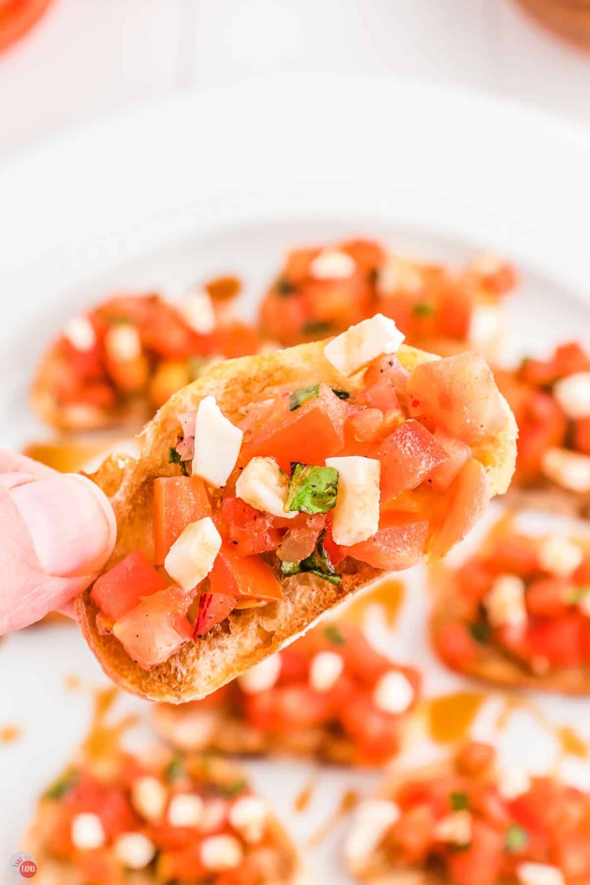 hand holding a piece of bruschetta