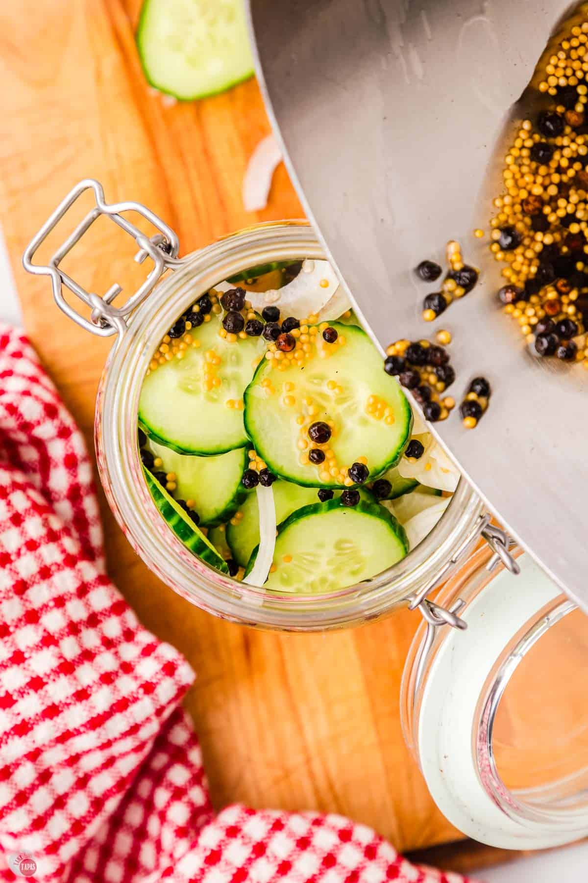 pot pouring pickle brine in a jar of sliced cucumbers