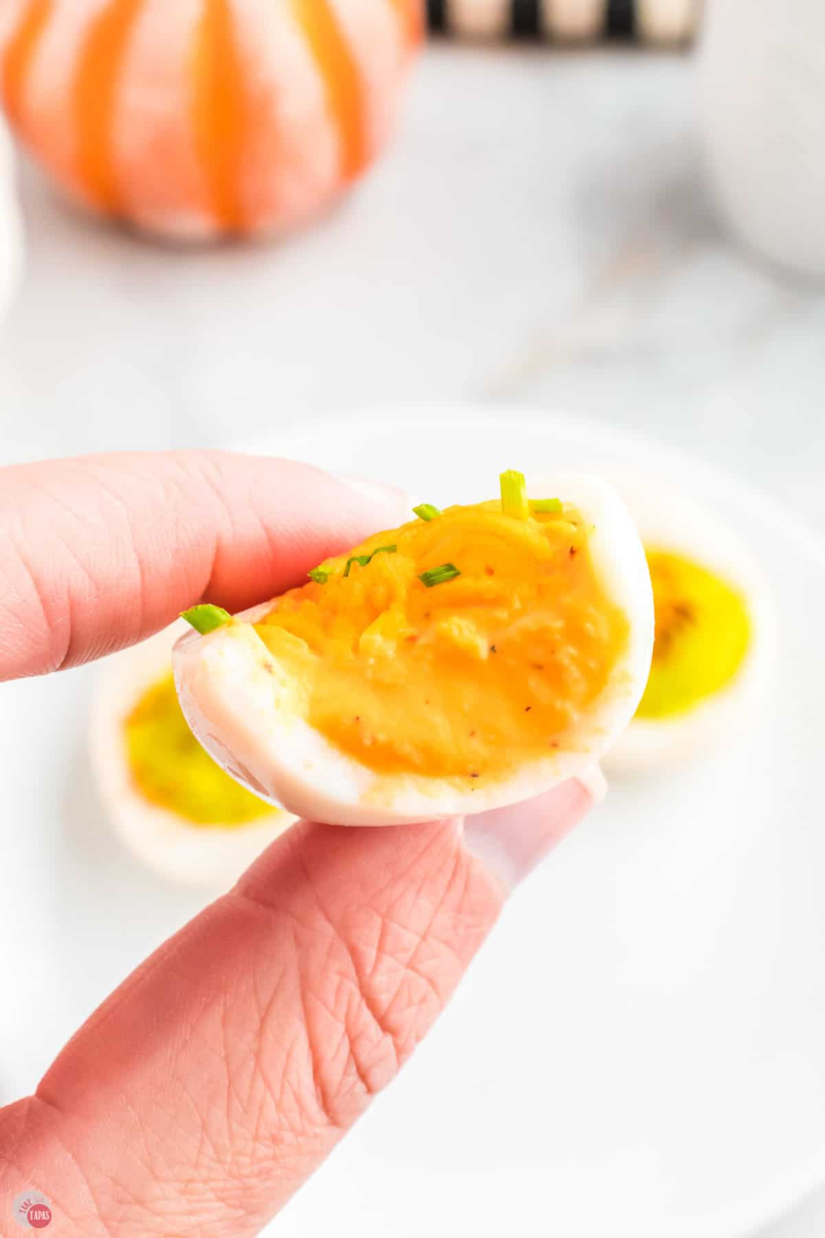 hand holding orange deviled egg for halloween