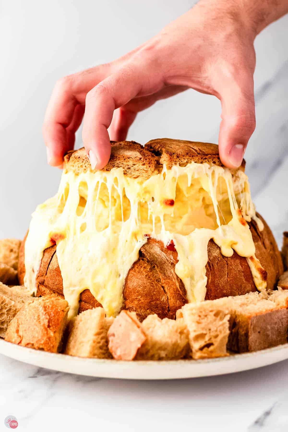 beer cheese dip in a bread bowl with the top being pulled off
