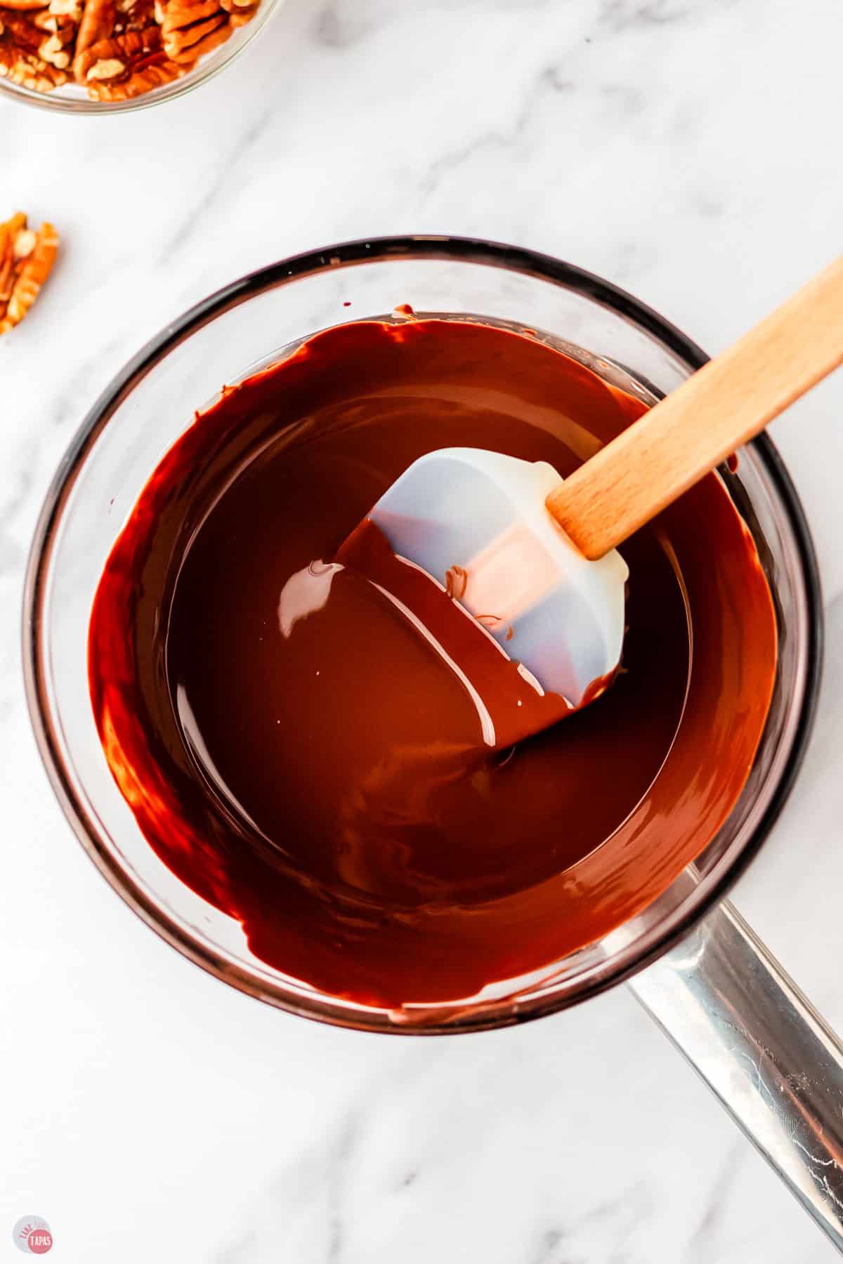 bowl of chocolate and coconut oil melted in a bowl with a clear spatula