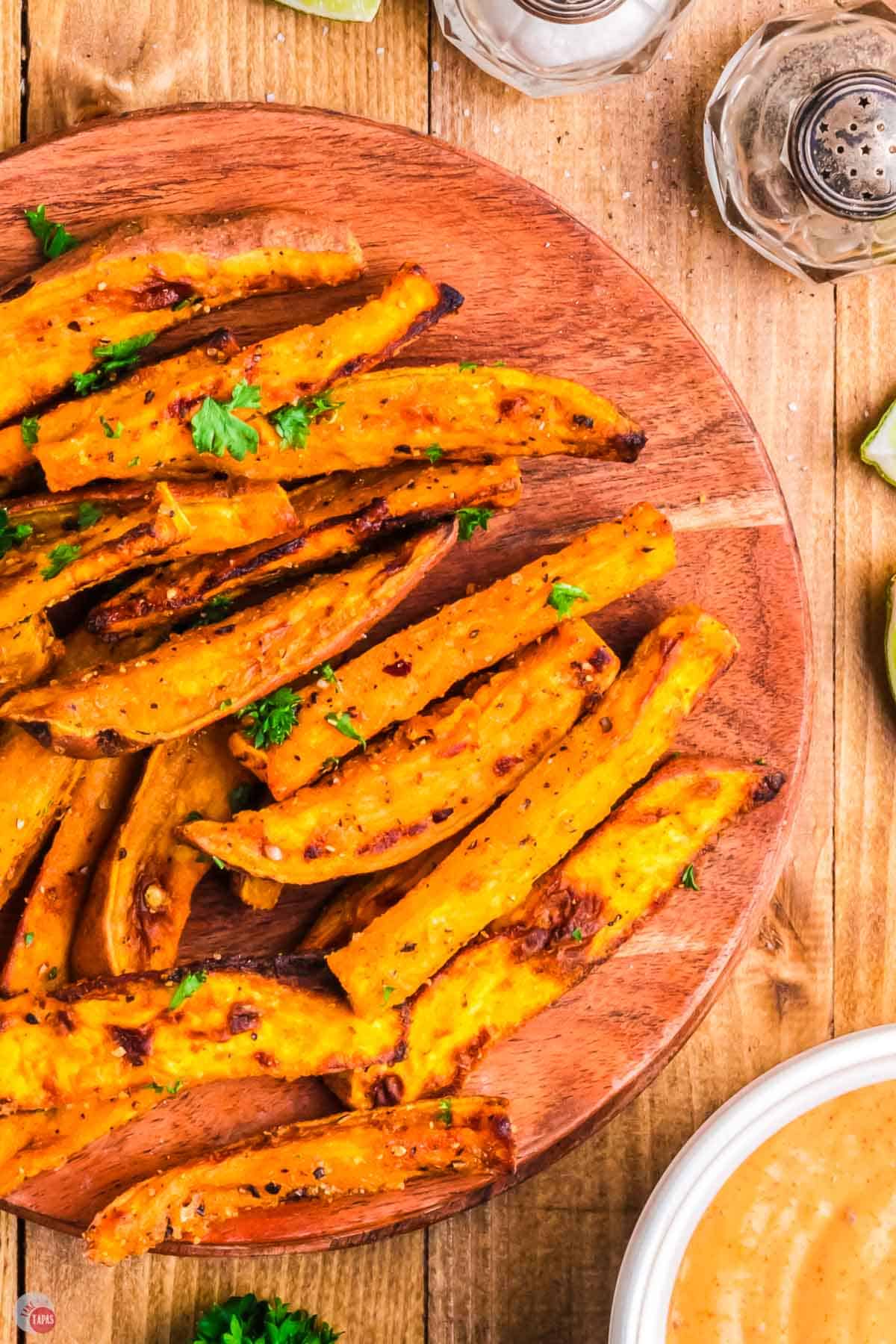 close up of sweet potato wedges on a wood cutting board