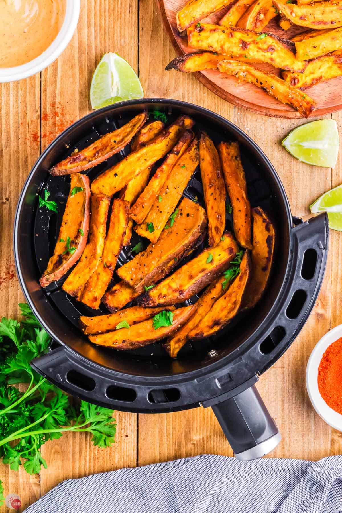 air fryer basket on a wood board with potato wedges in it