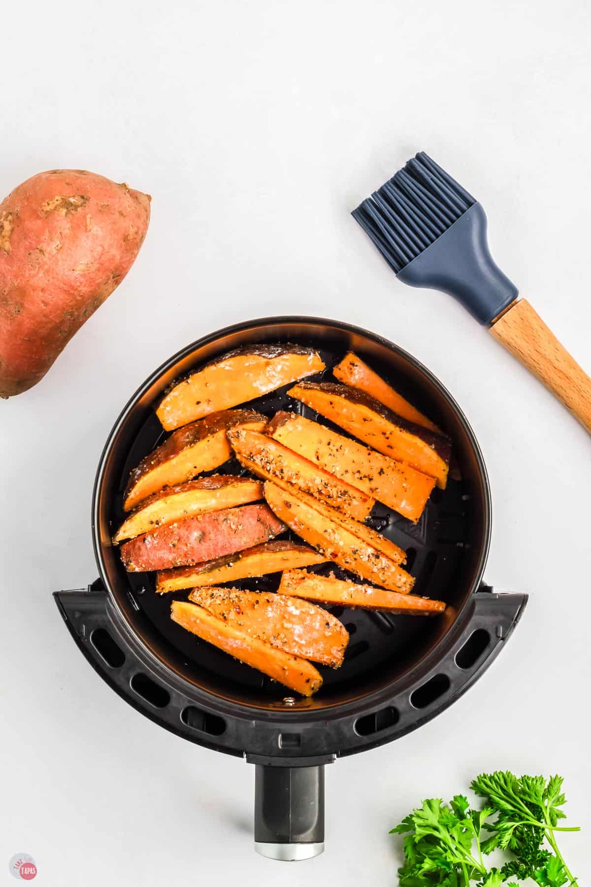 sliced sweet potatoes in an air fryer basket