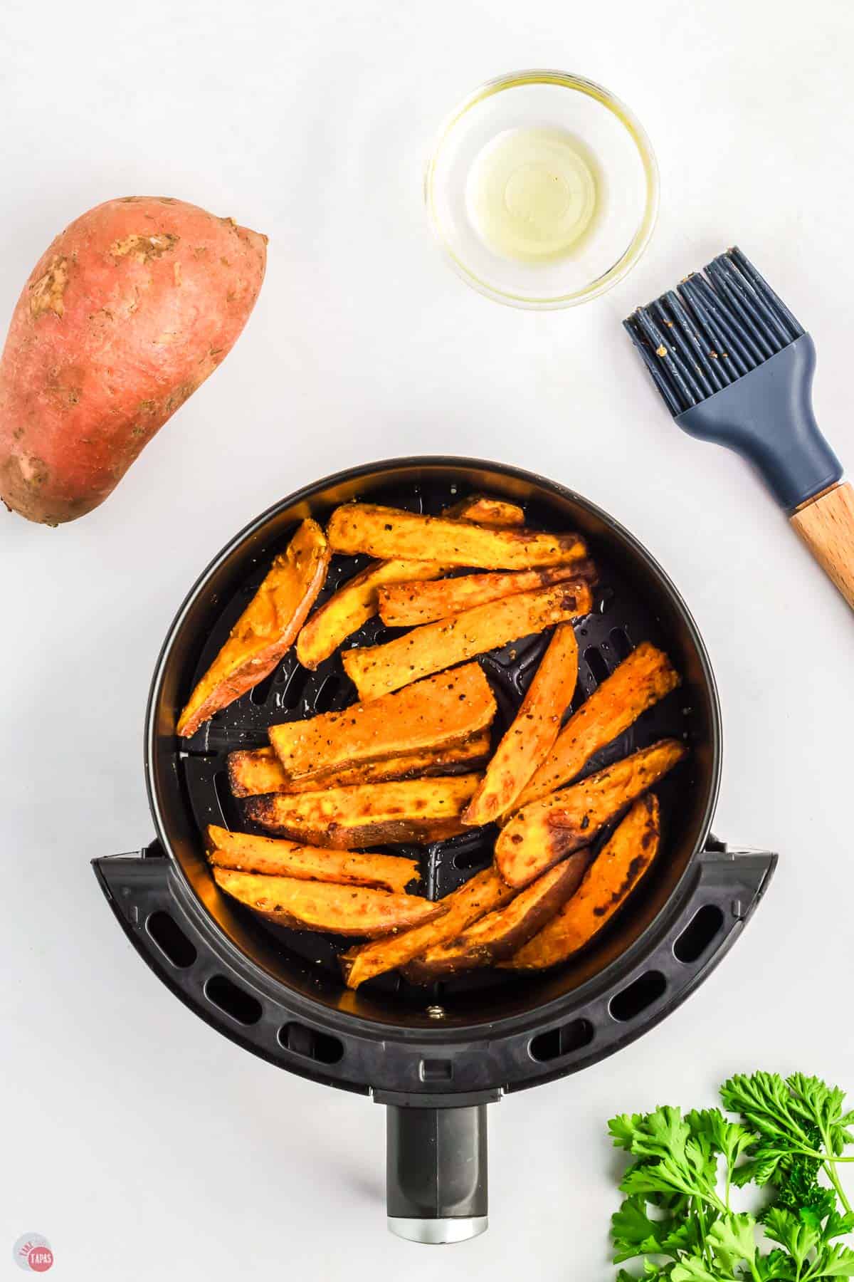 cooked sweet potato wedges in an air fryer basket