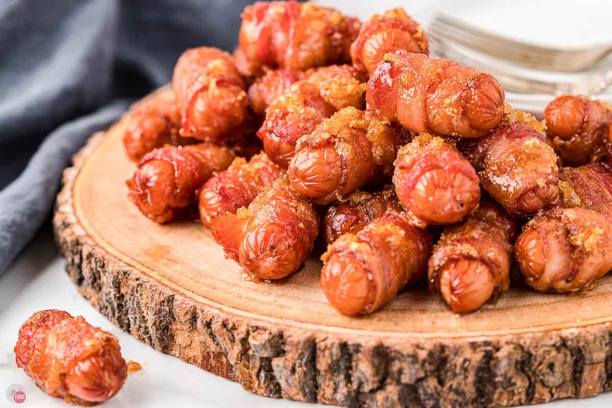 wood plate with bacon wrapped smokies piled on it