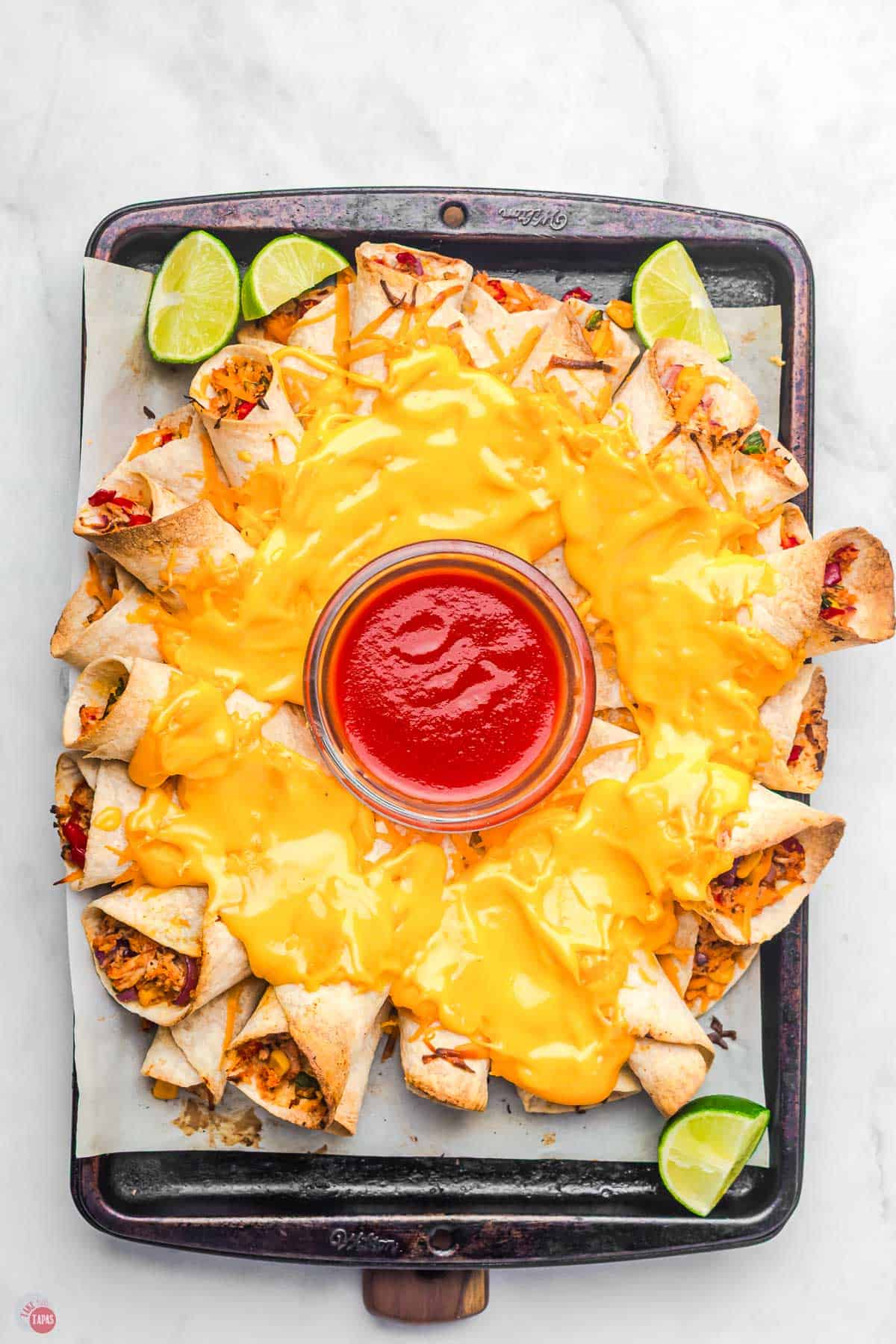 baked blooming quesadilla ring on a baking sheet with a bowl of salsa in the middle