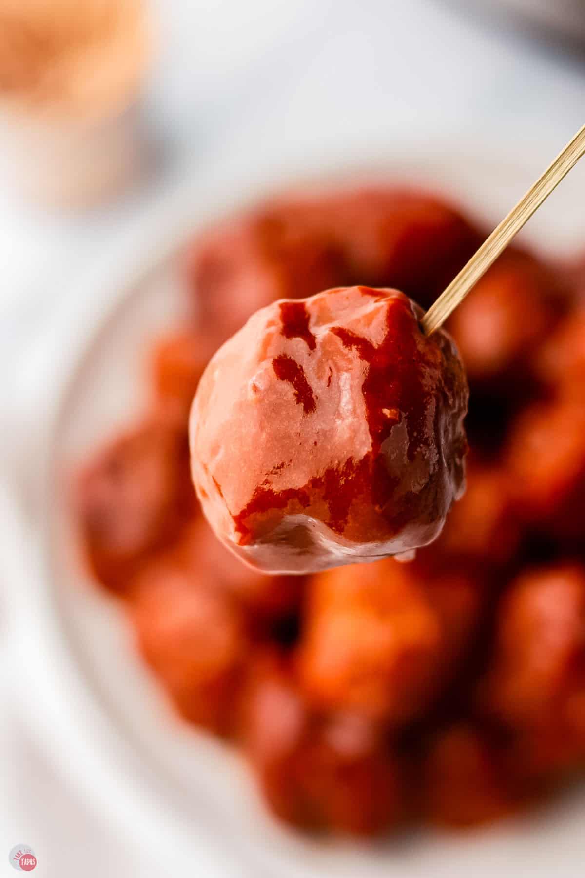 close up of meatball covered in sauce on a toothpick