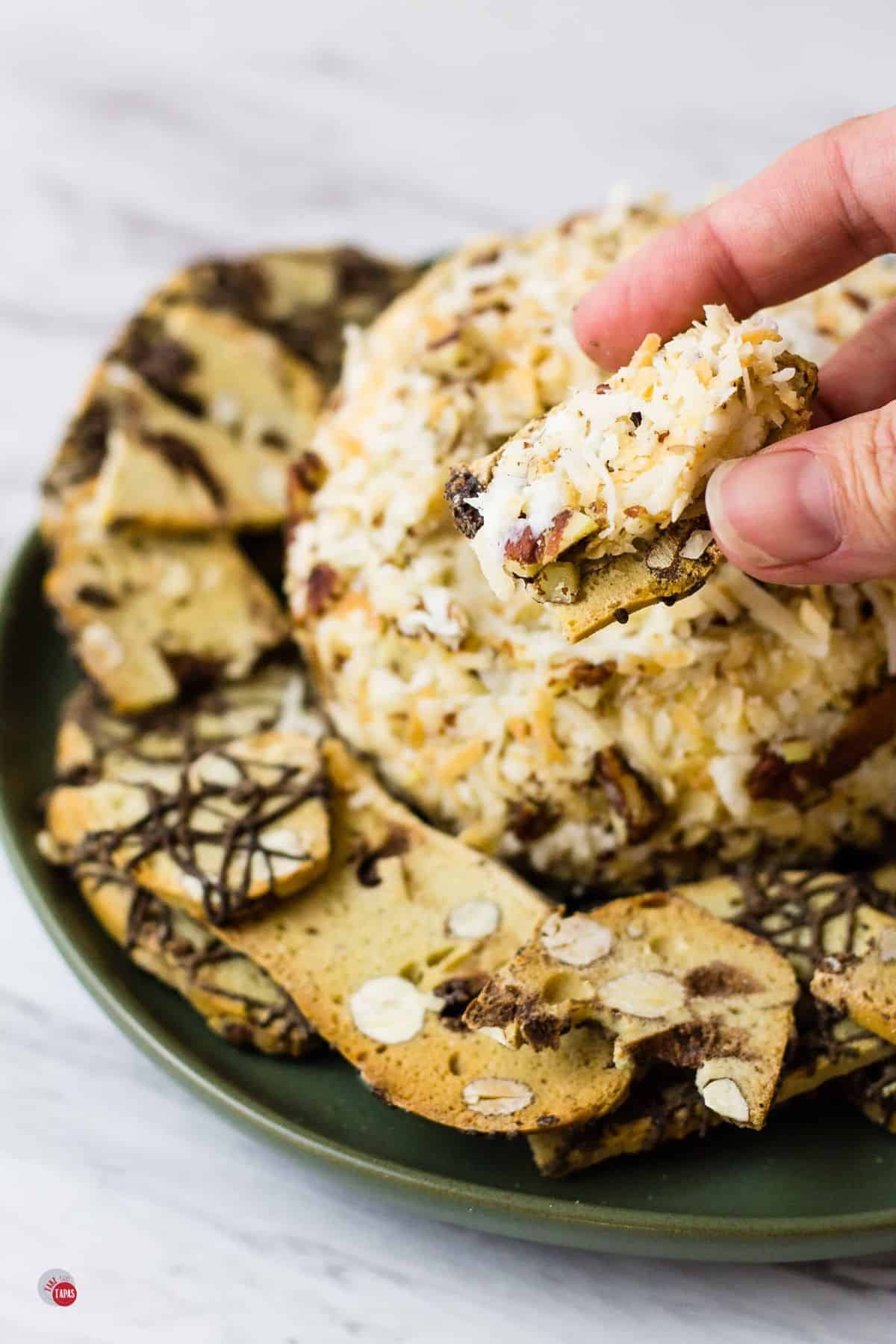 hand holding a cracker with cream cheese on it