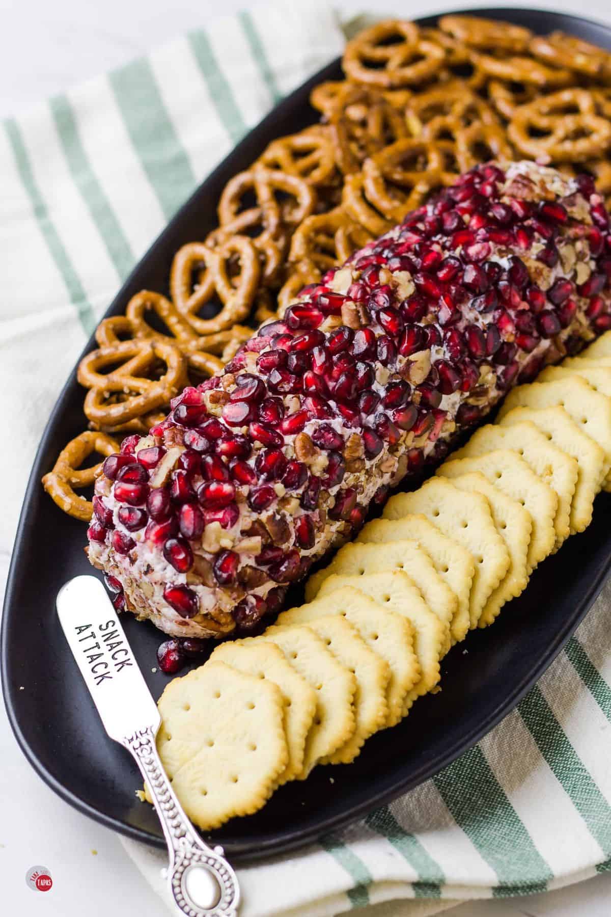 pomegranate goat cheese log with crackers and a spreader