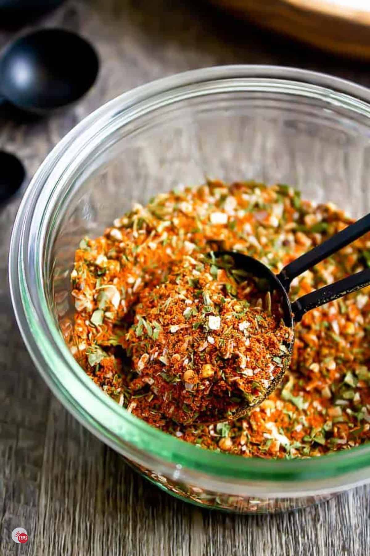 jar of southwest seasoning with black measuring spoons next to it