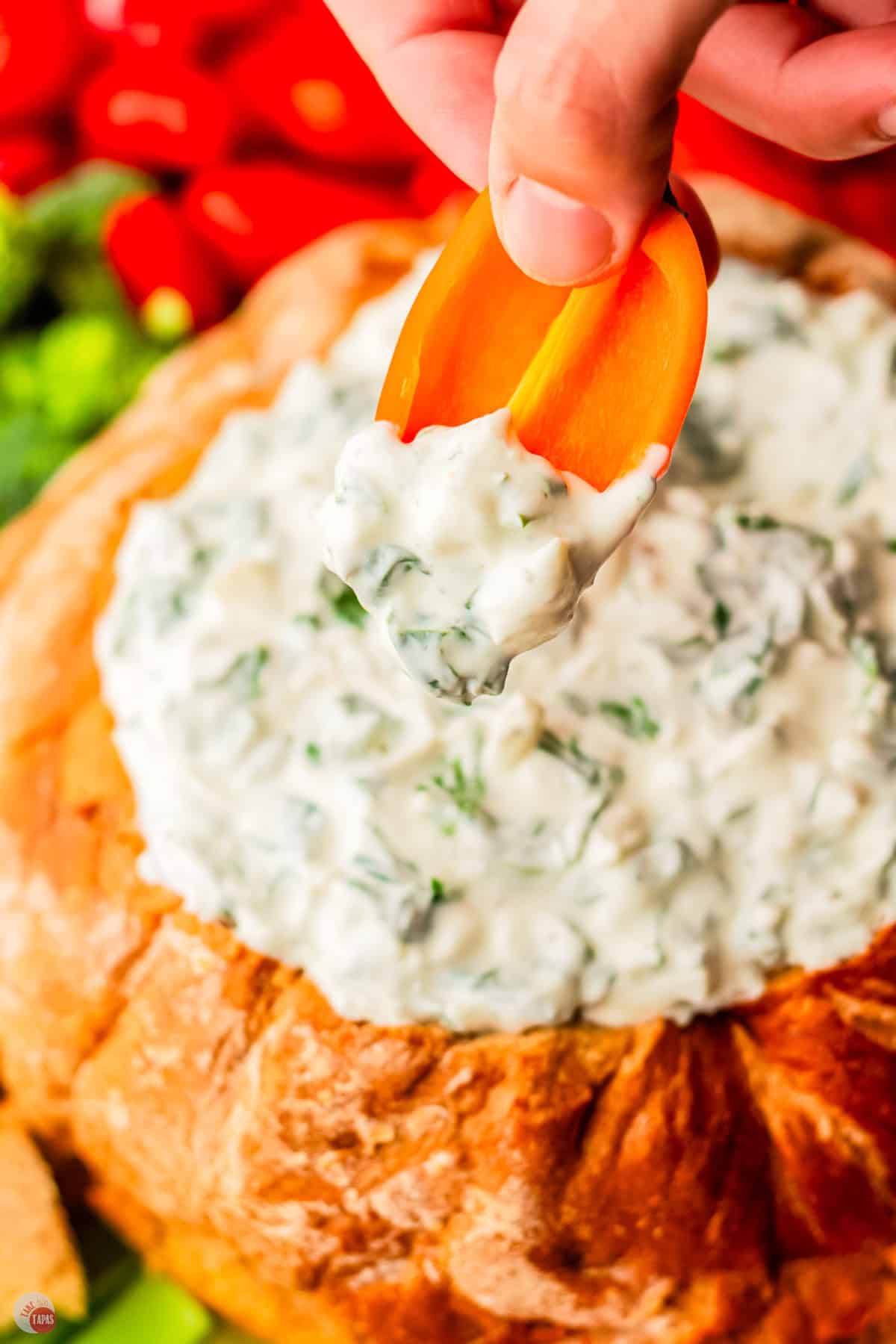 bell pepper being dipped into spinach dip