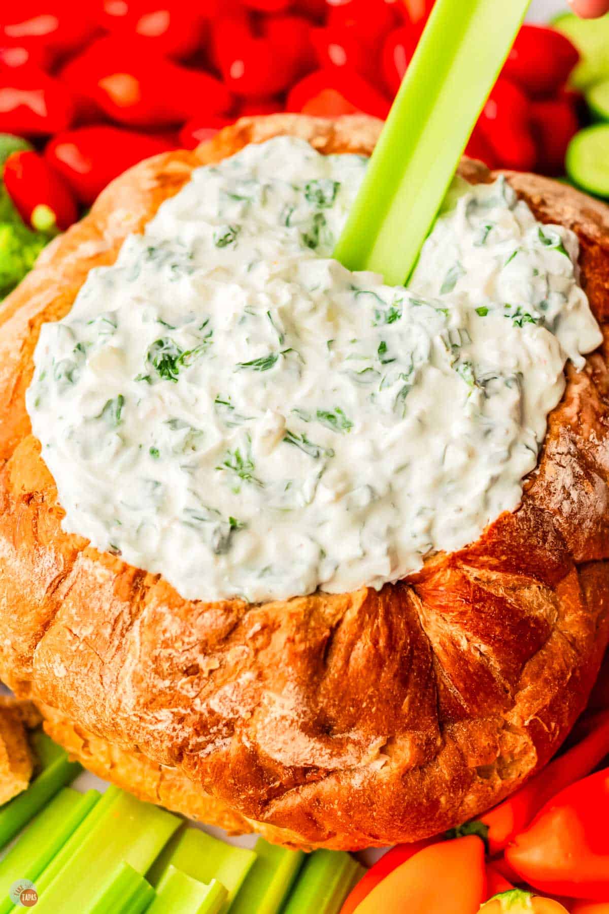 spinach dip bread bowl with a celery stick in the dip