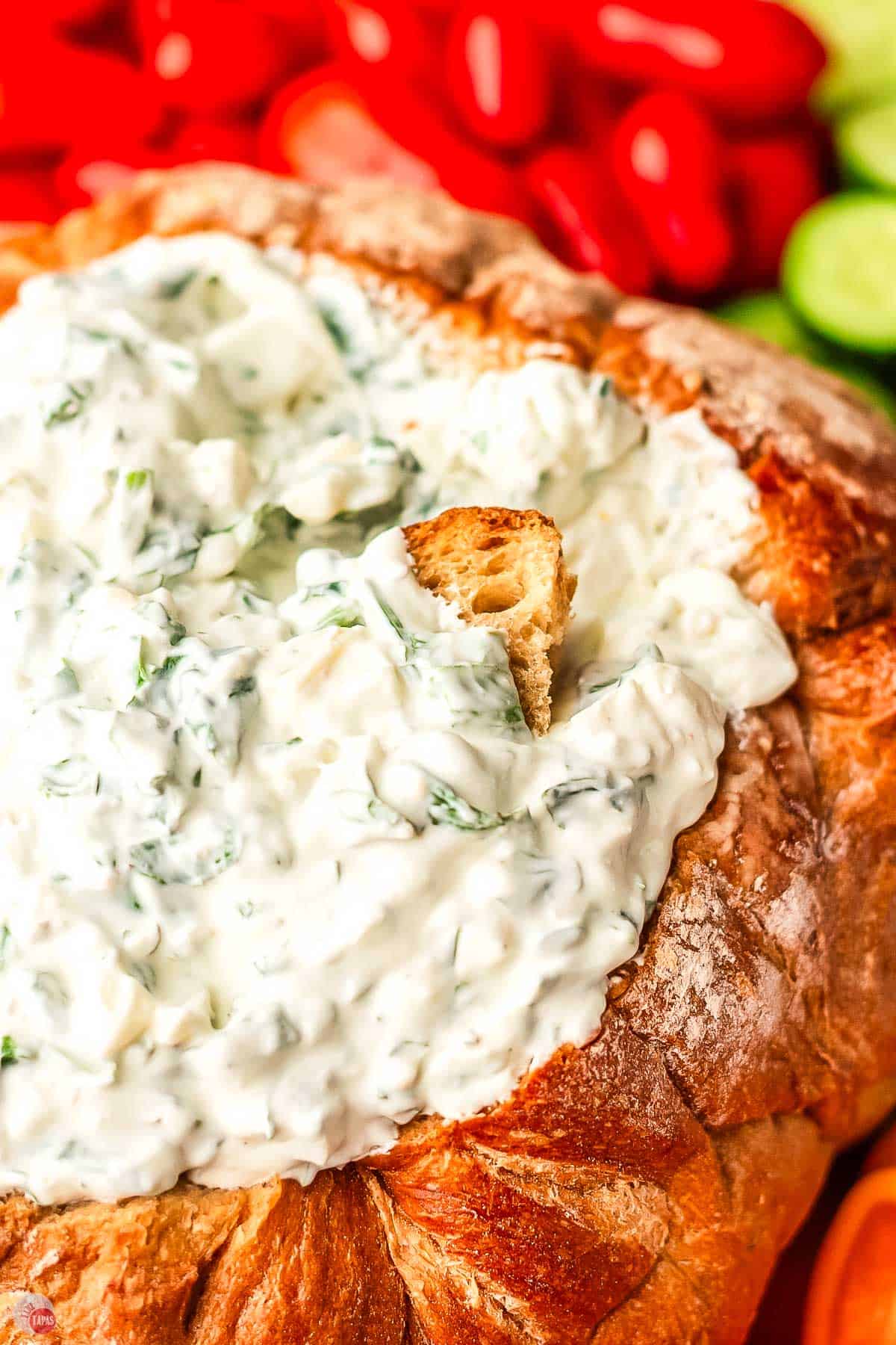 bowl of spinach dip with bread piece in it