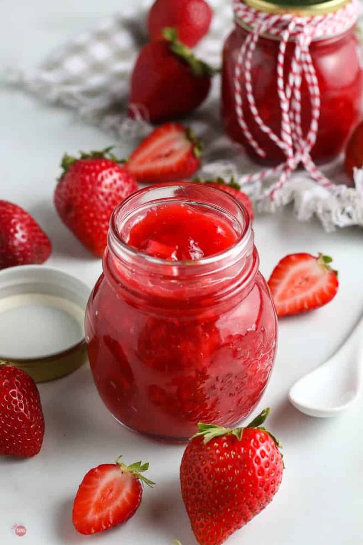 jar of strawberry sauce surrounded by fruit