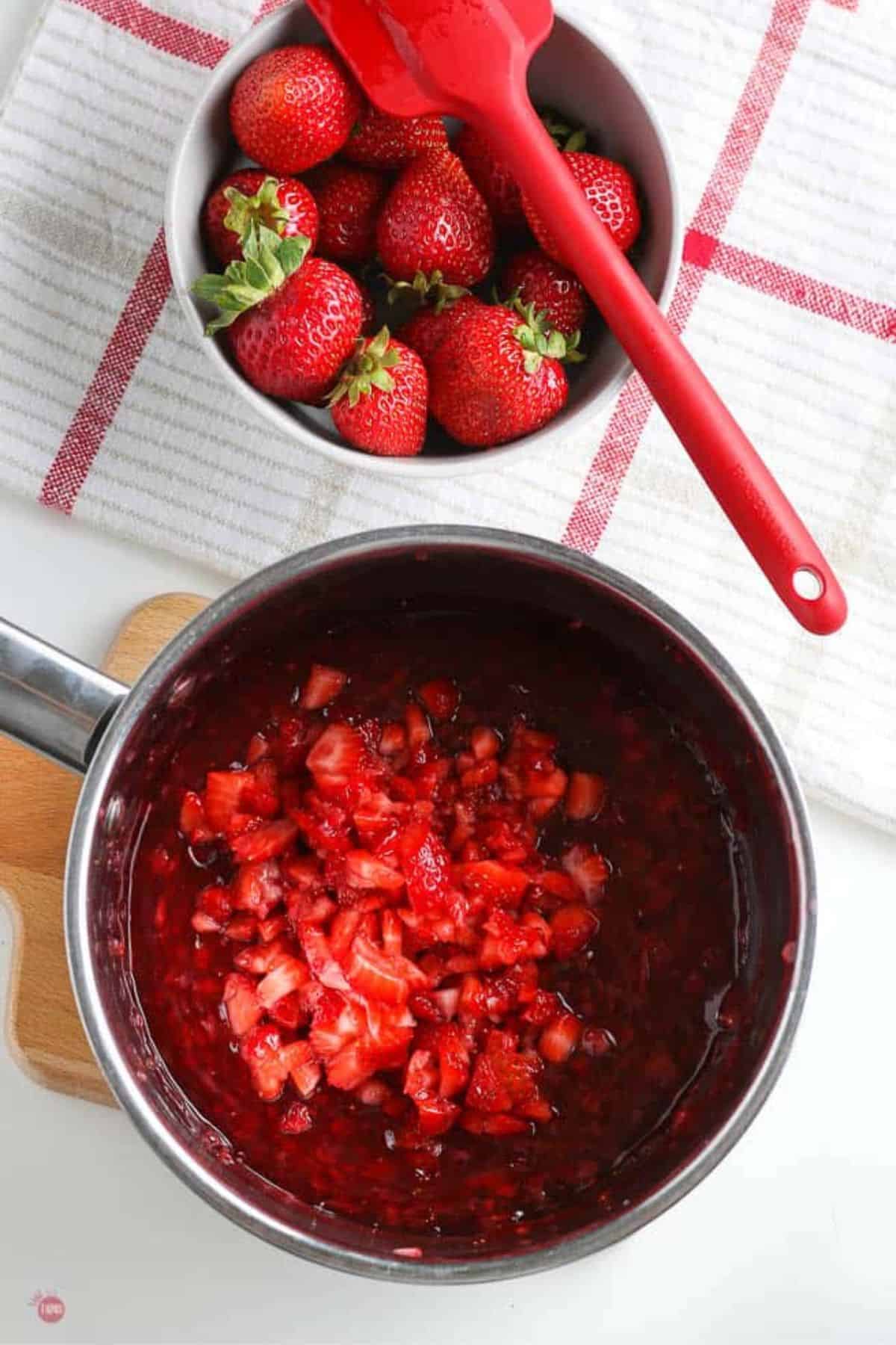 fresh strawberries in a pot with a bowl of fruit next to it