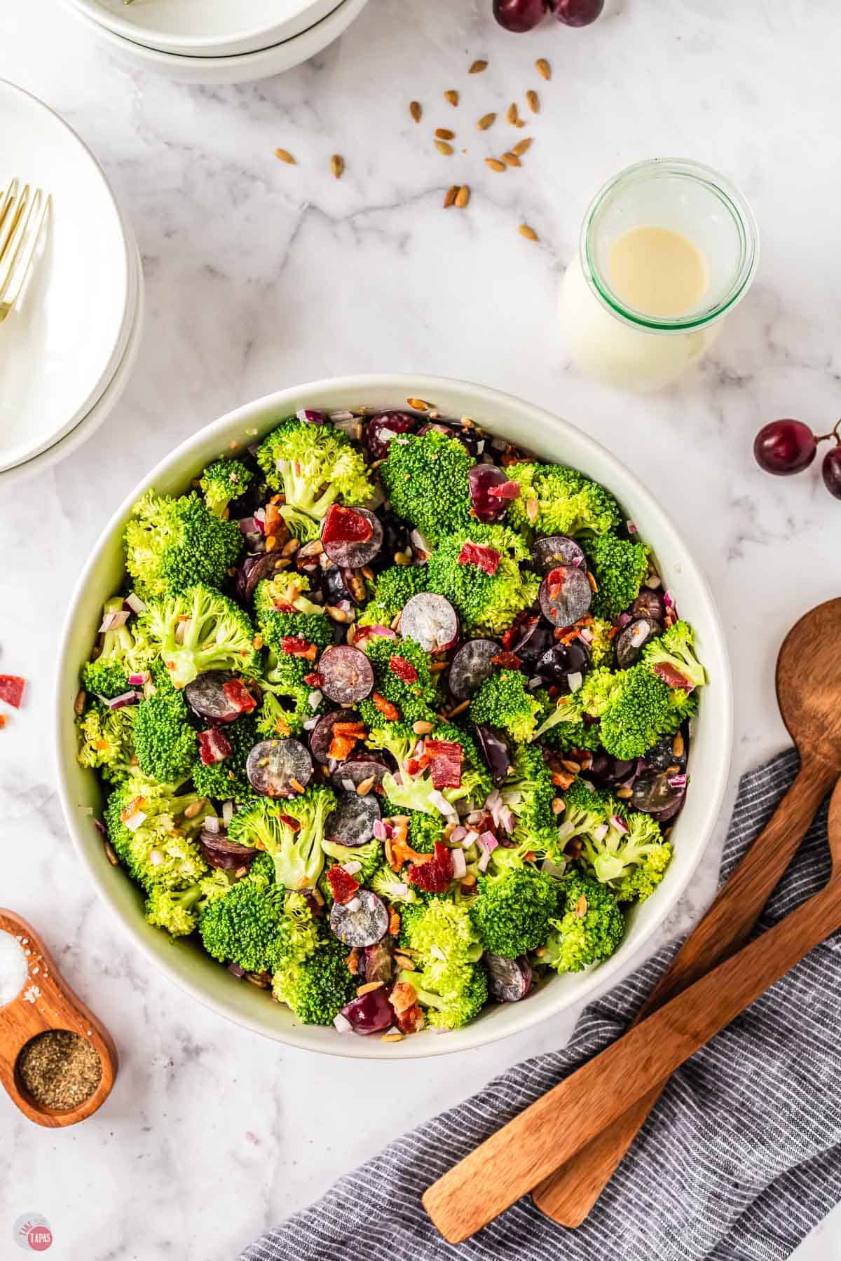 overhead picture of a broccoli grape salad recipe with two wooden spoons next to it
