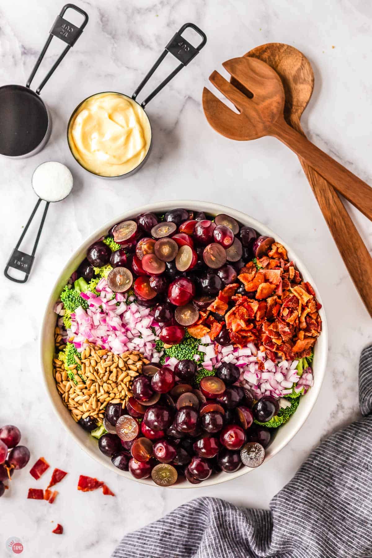 unmixed salad ingredients in a white bowl and set of wood spoons