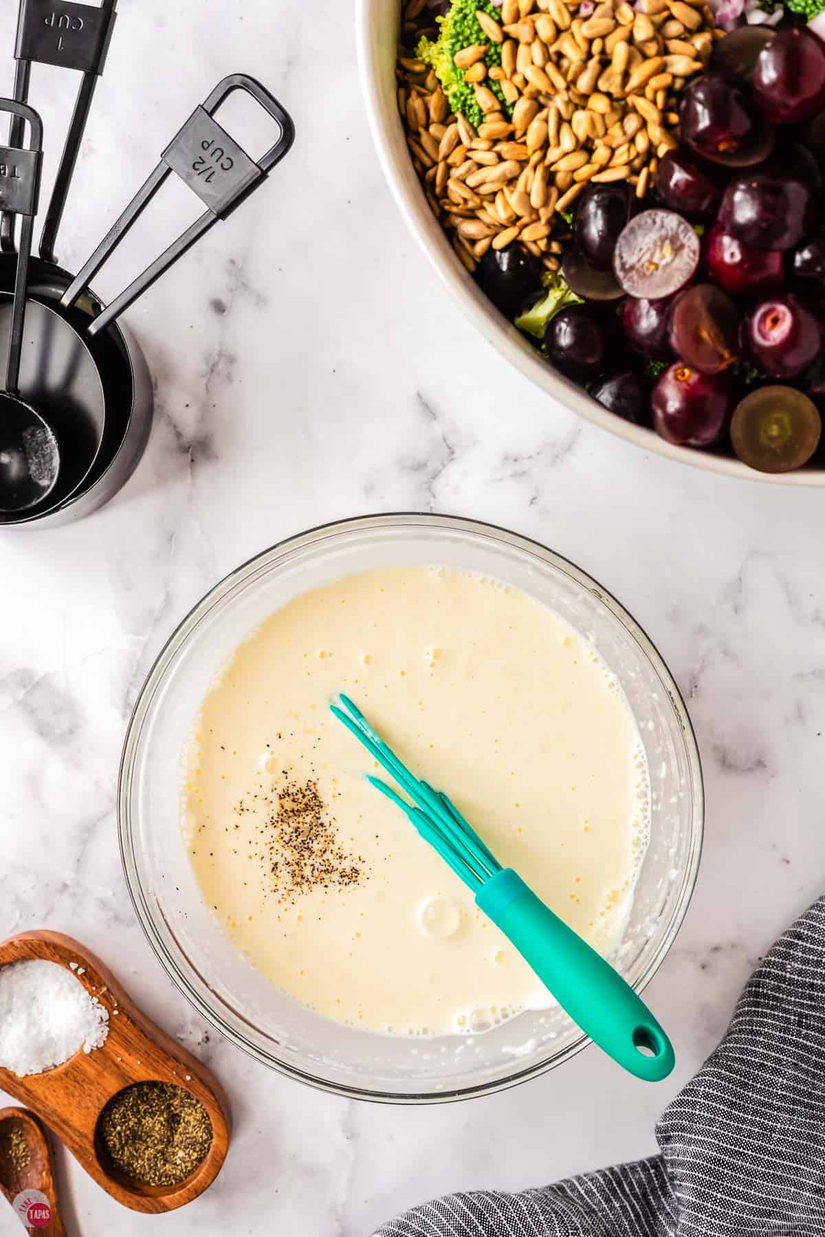 dressing mixed in a bowl with a blue whisk