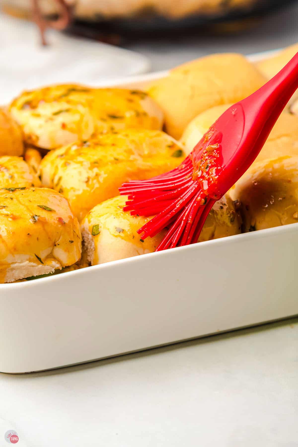 slider buns with butter being brushed on the top
