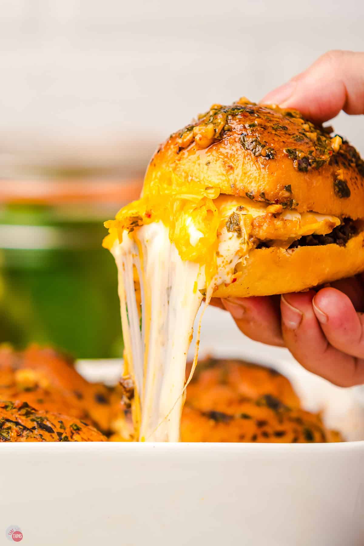 hand pulling a small burger out of a pan