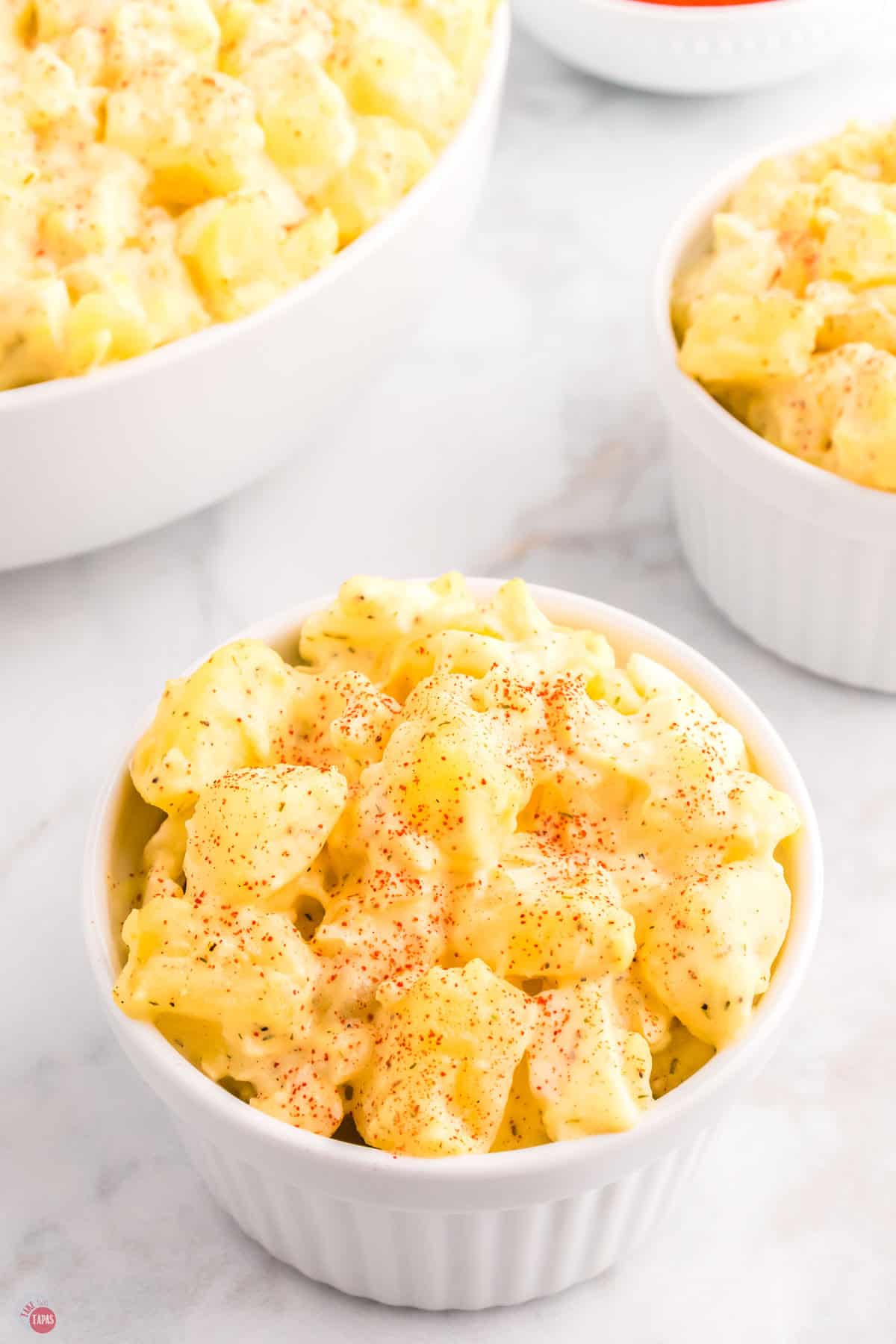 small bowl of cream potato salad topped with a sprinkle of paprika