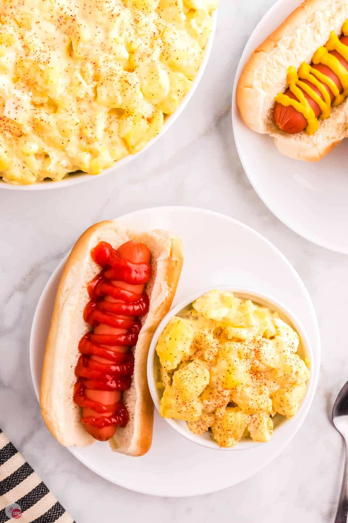 plate with ketchup topped with mustard and a small bowl of potatoes