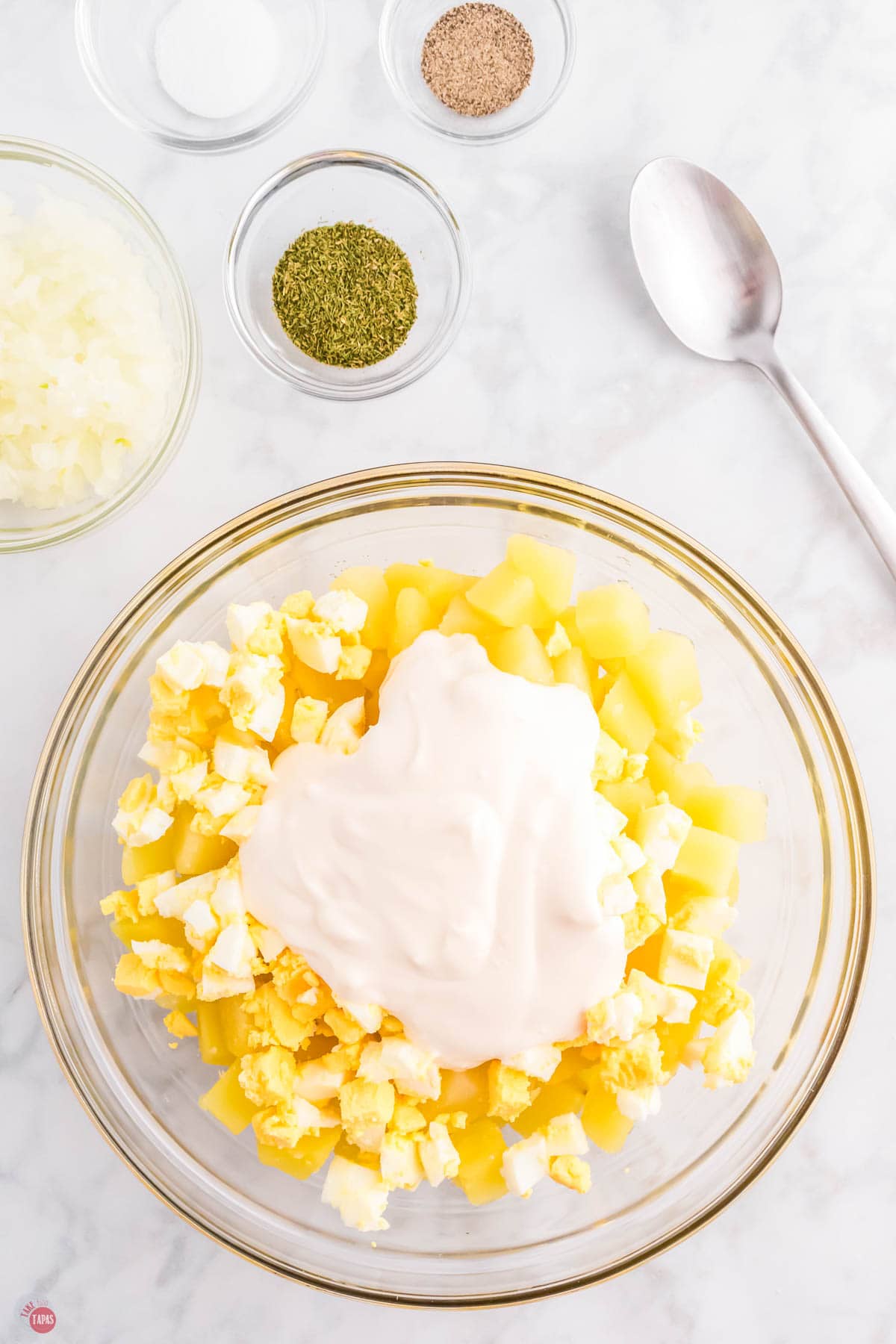 diced potatoes, diced hard boiled egg, and mayo in a clear bowl