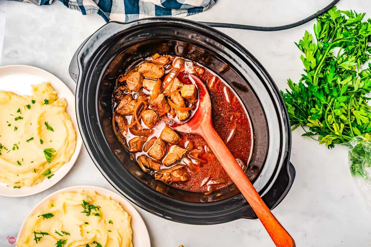 A slow cooker with meat and gravy.