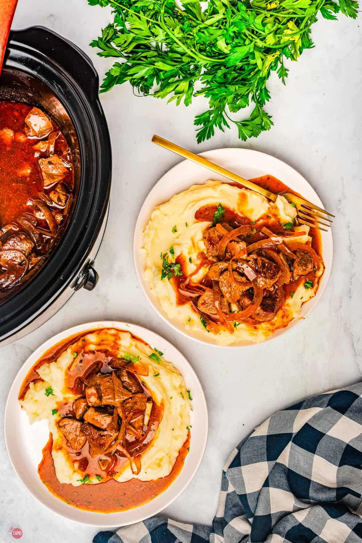 two plates of mashed potatoes with steak bites on them and some gravy