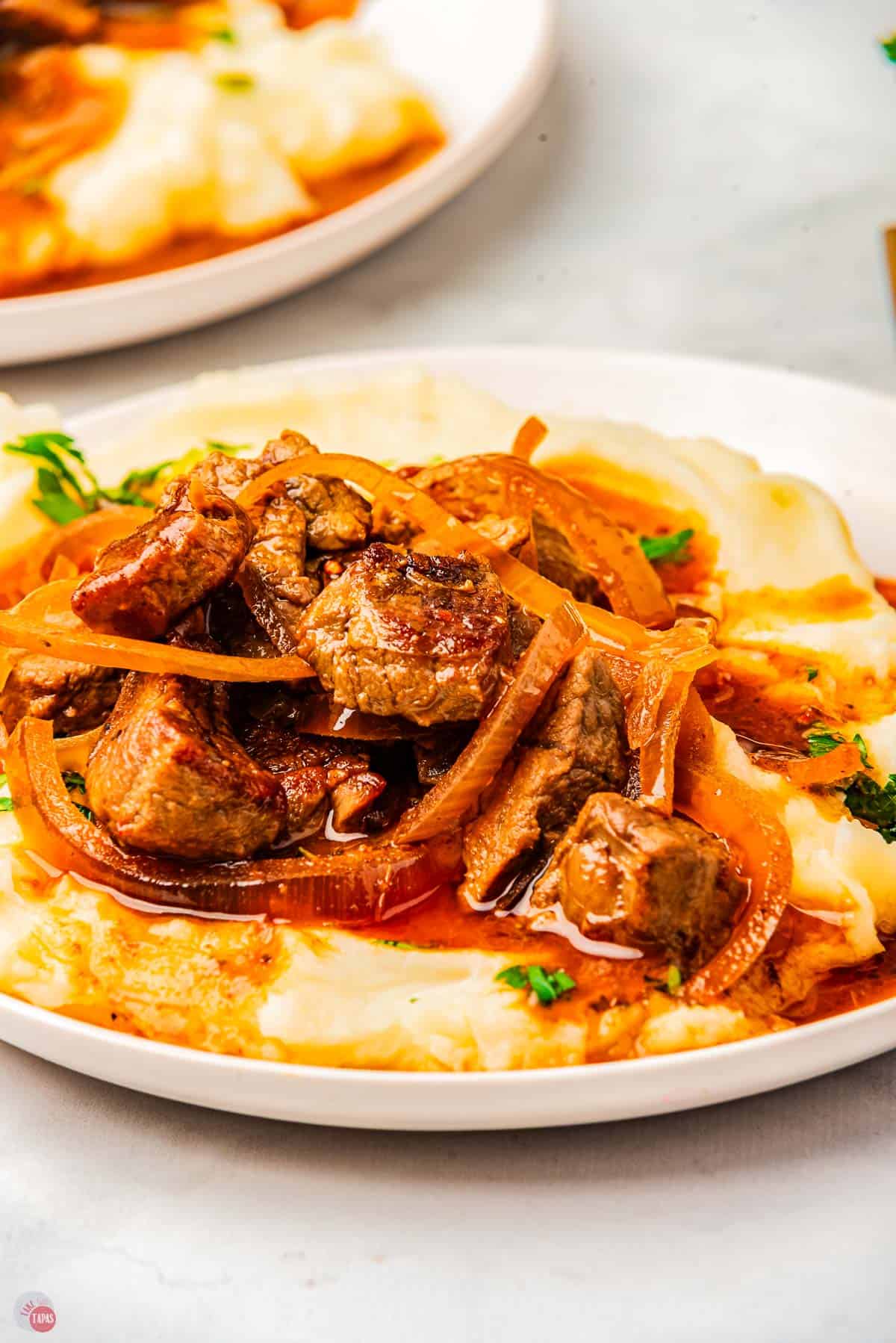 close up of steak bites on top of mashed potatoes with gravy