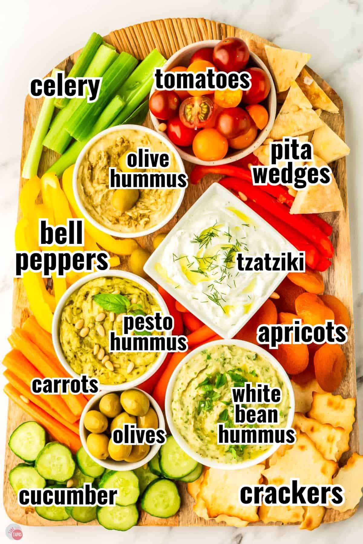 ingredients for a mezze platter on a wood board with text overlay labeling them