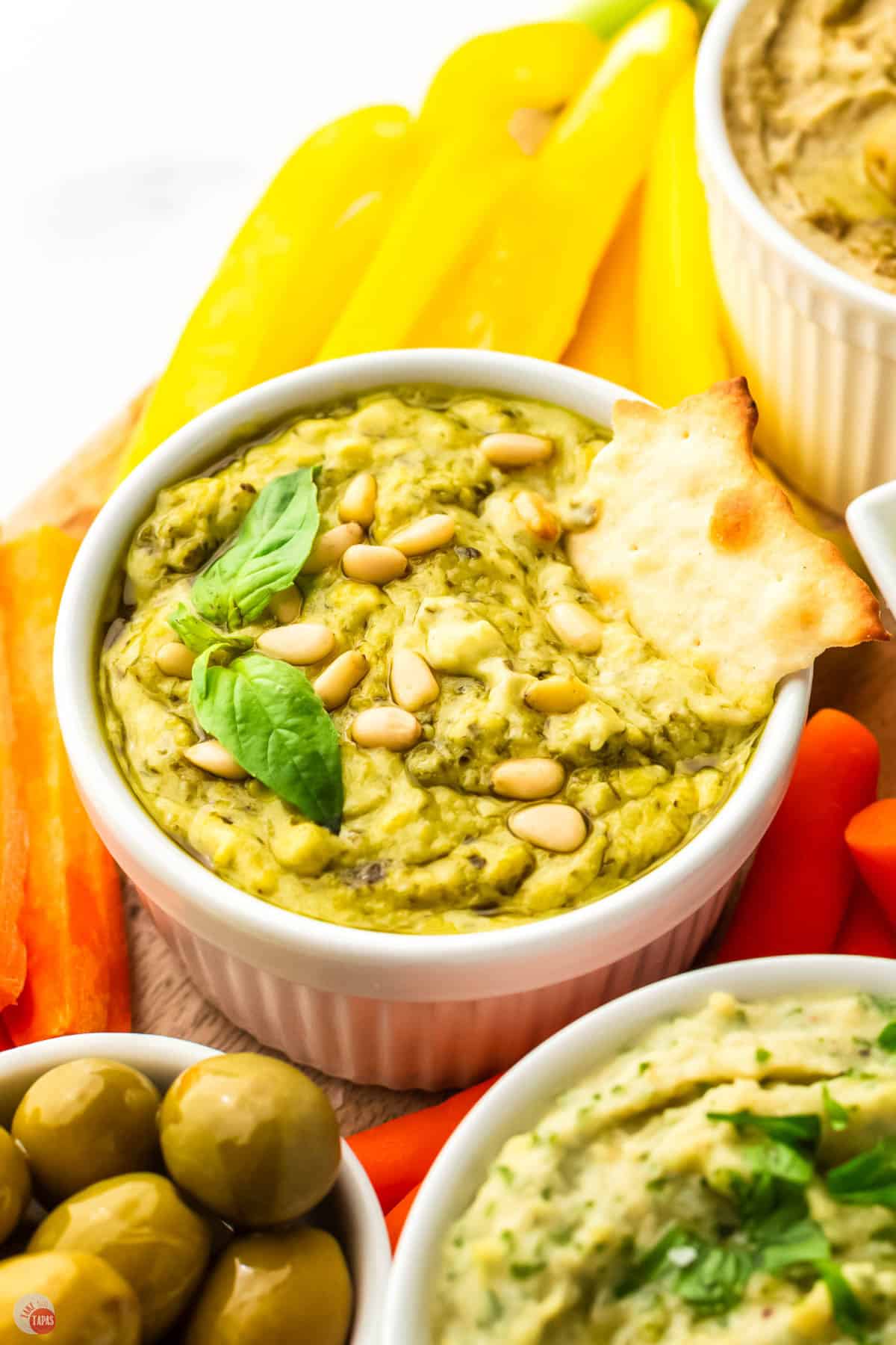 close up of pesto hummus with cracker in it