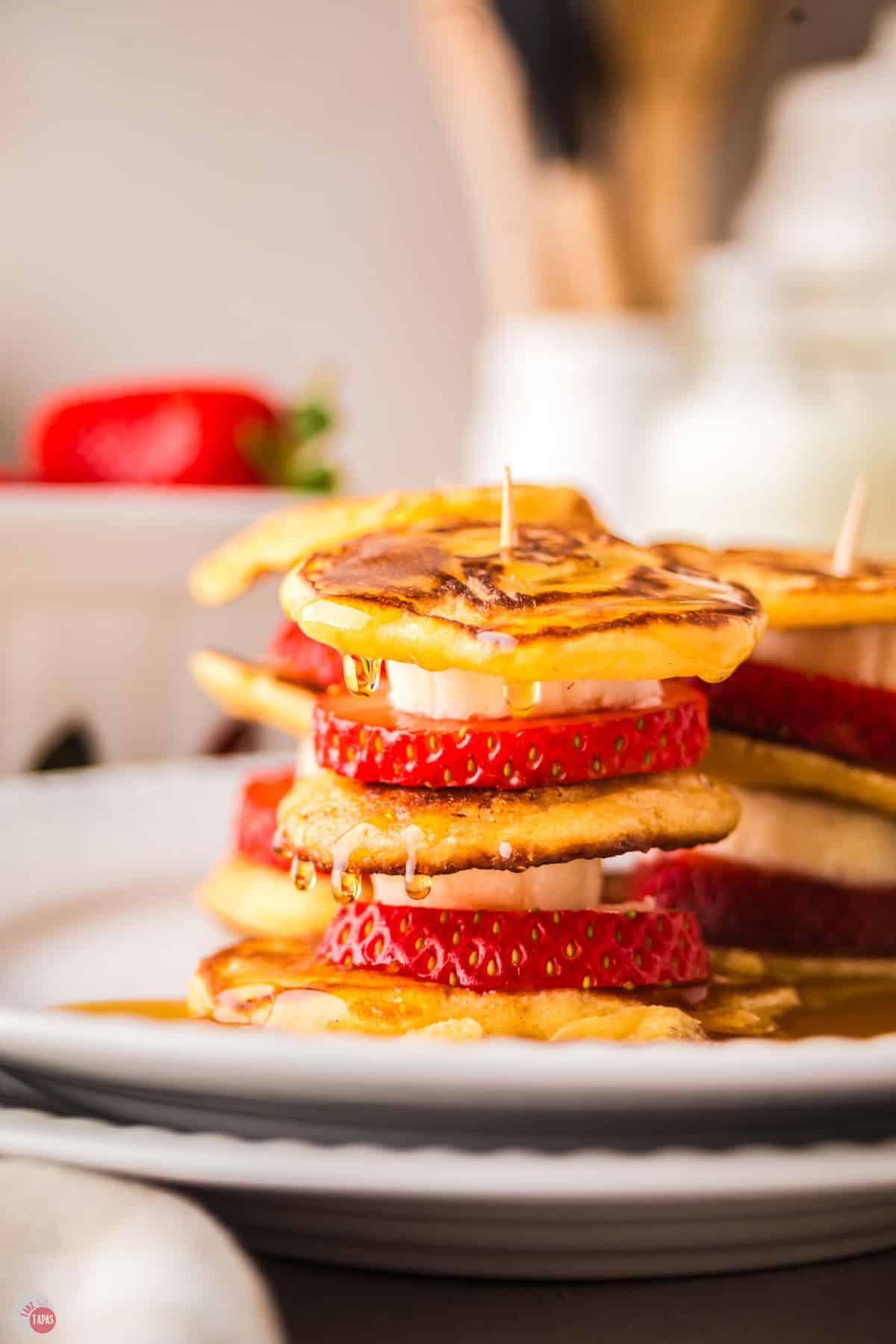 stack of mini pancakes with sliced bananas and strawberries in between them